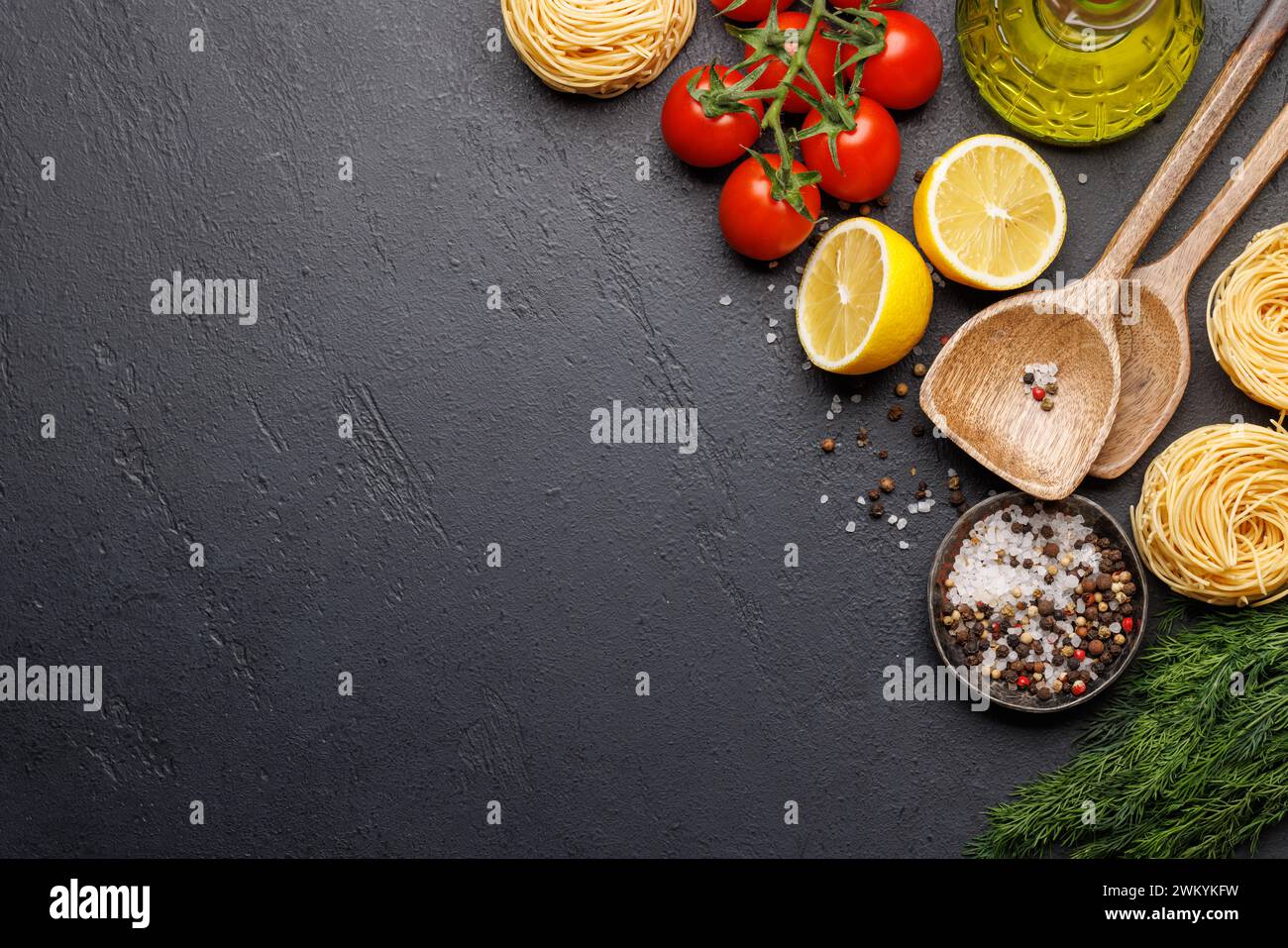 Kochszene: Kirschtomaten, Nudeln, Gewürze auf dem Tisch. Flache Ladefläche mit Kopierraum Stockfoto