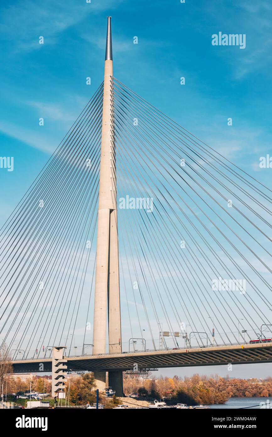 Die Hängebrücke ist ein modernes Wunder der Ingenieurskunst und überspannt den Fluss vor dem Hintergrund des klaren blauen Himmels mit komplizierten Kabeln und Stahlbögen Stockfoto