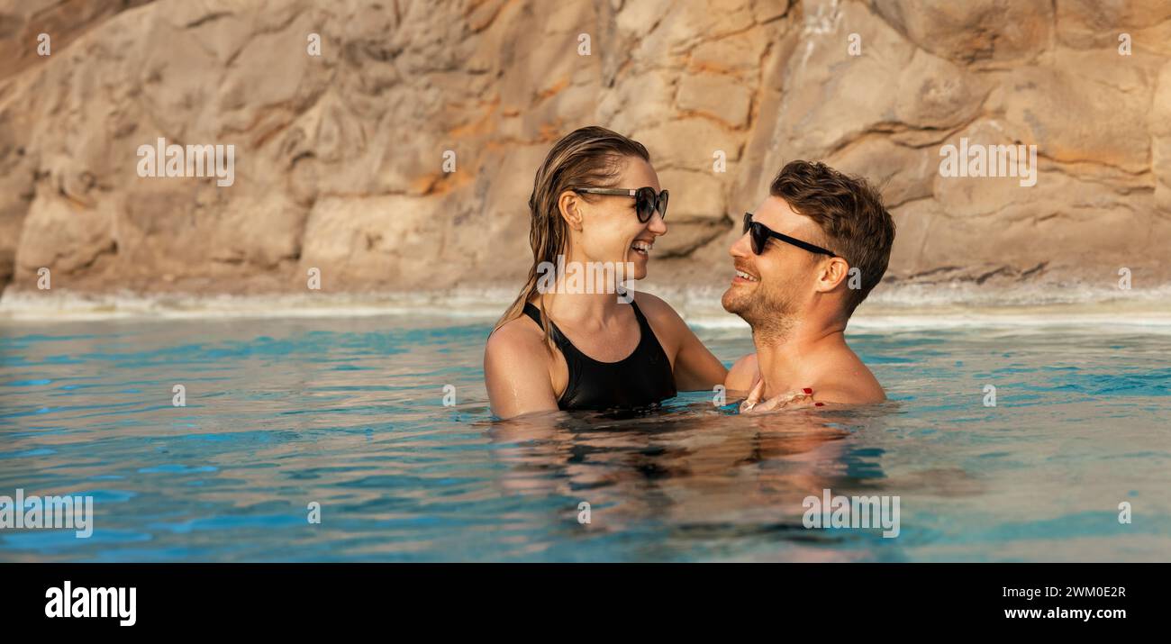 Glückliches Paar, das im Swimmingpool kuschelt. Romantischer Kurzurlaub. Banner mit Kopierbereich Stockfoto