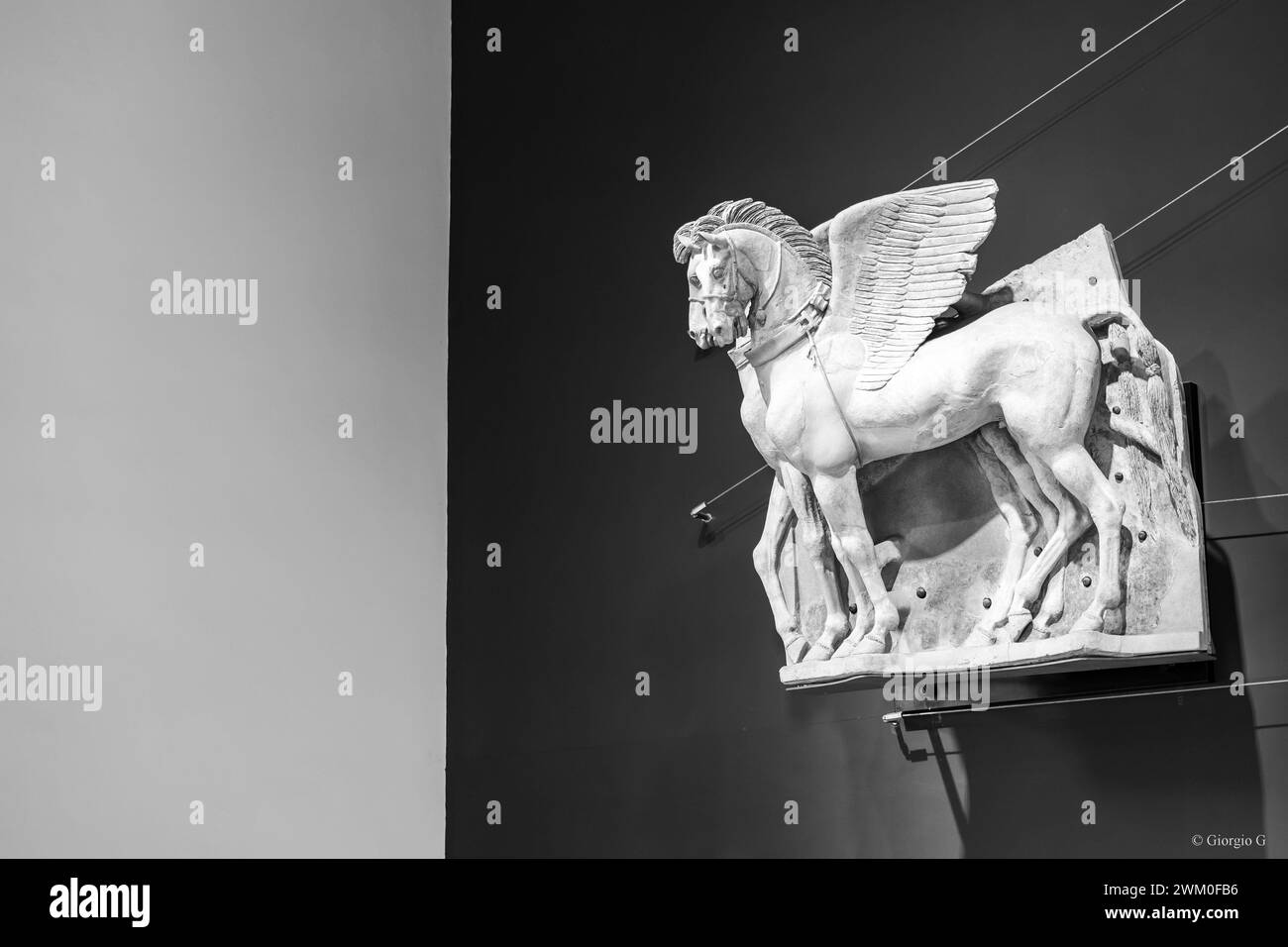 Schwarz-weiß-Foto eines antiken dekorativen Stücks, das Pegasus zeigt, der in eine Marmorwand geschnitzt ist Stockfoto