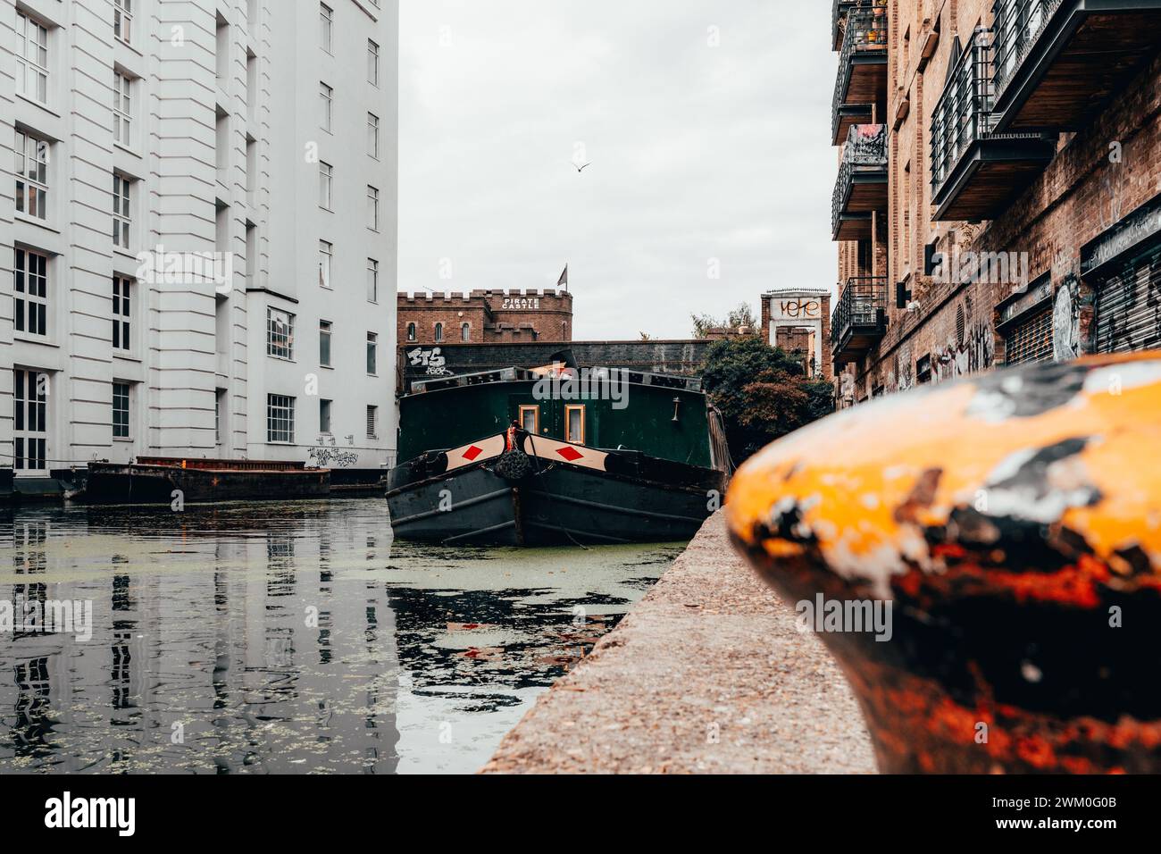 Ein Boot fährt eine enge Wasserstraße hinunter, London, Großbritannien Stockfoto