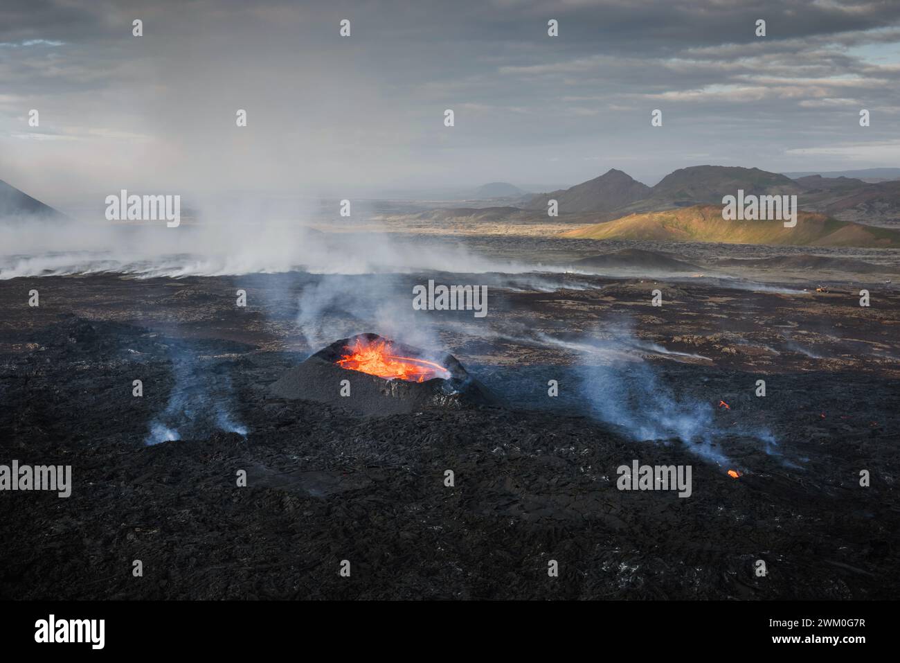 Apokalyptische Umgebung eines Vulkanausbruchs, rote heiße Lava, die den Krater hinunterkocht und hinunter strömt, vulkanische Gase und Rauch, die sich um das Gebiet ausbreiten; Stockfoto