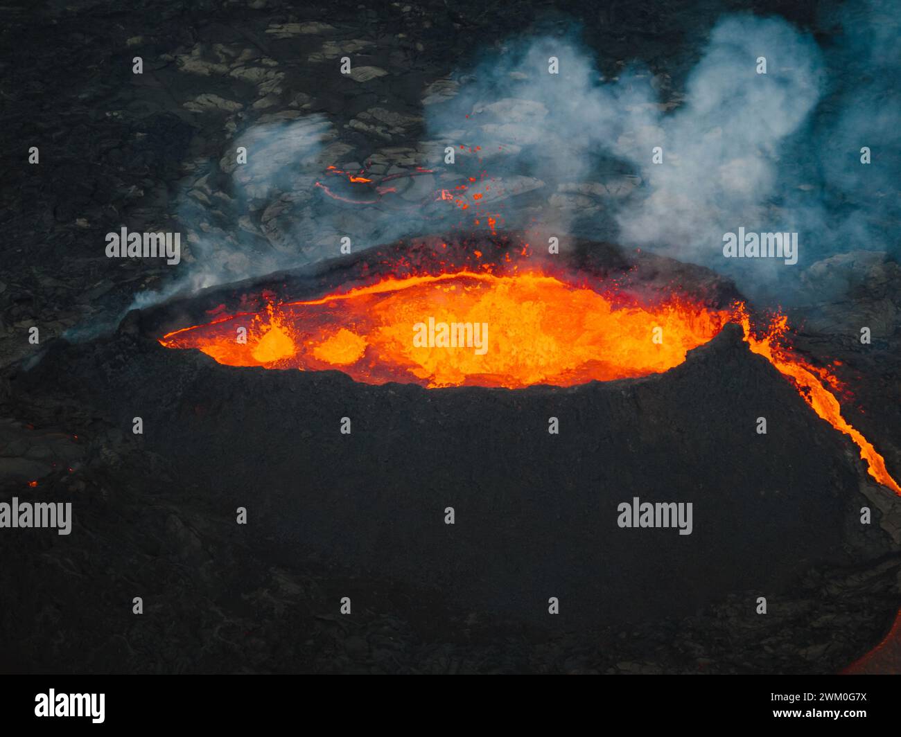 Fließende Lava, heißes Magma, das aus dem Vulkankrater fließt, Seitenansicht aus der Luft. Konzepte von Vulkanausbruch und isländischem Feuer- und Eisland. Stockfoto