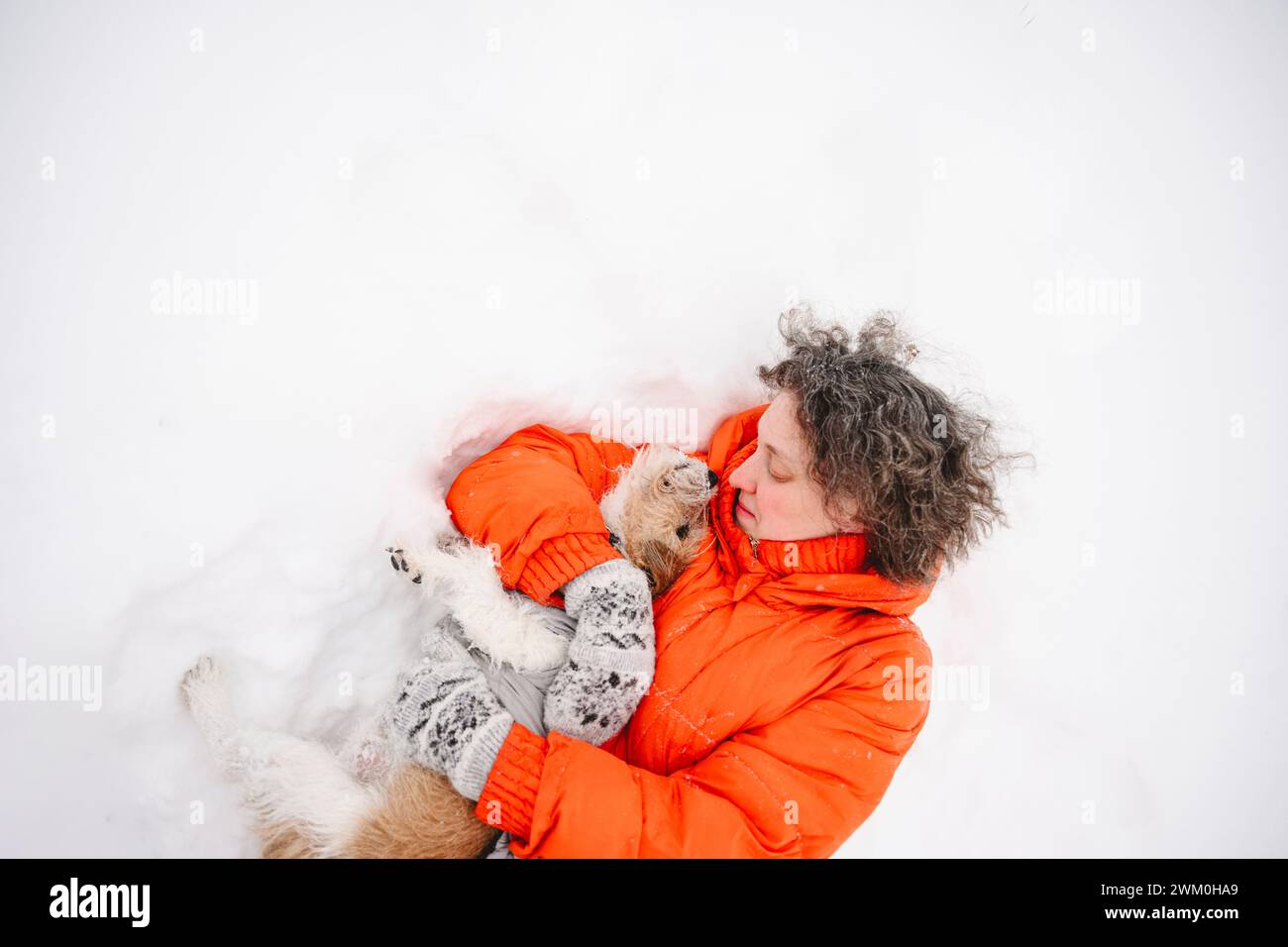 Frau liegt auf Schnee mit Hund Stockfoto