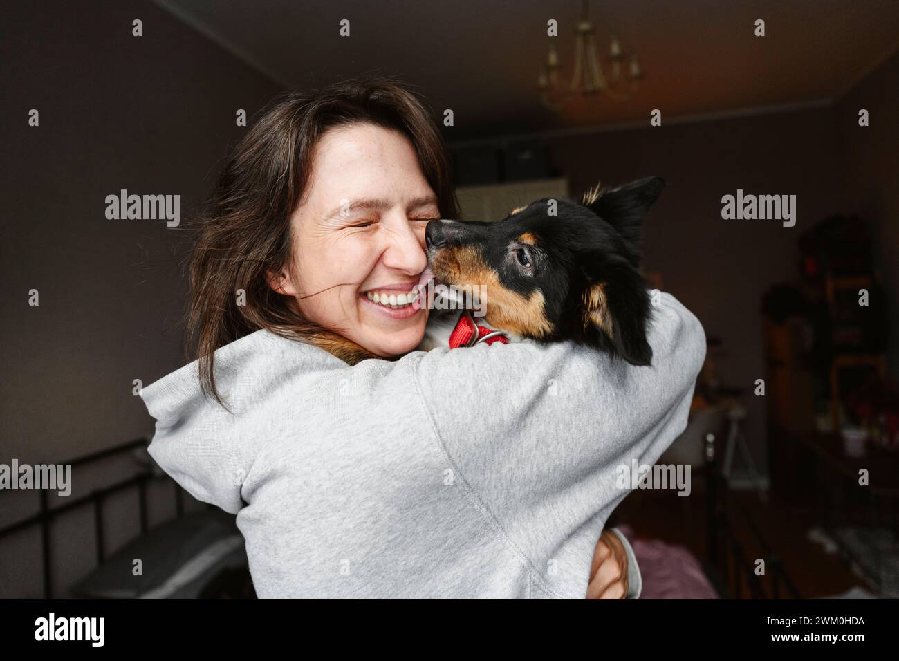 Glückliche Frau mit geschlossenen Augen, die Hund zu Hause hält Stockfoto