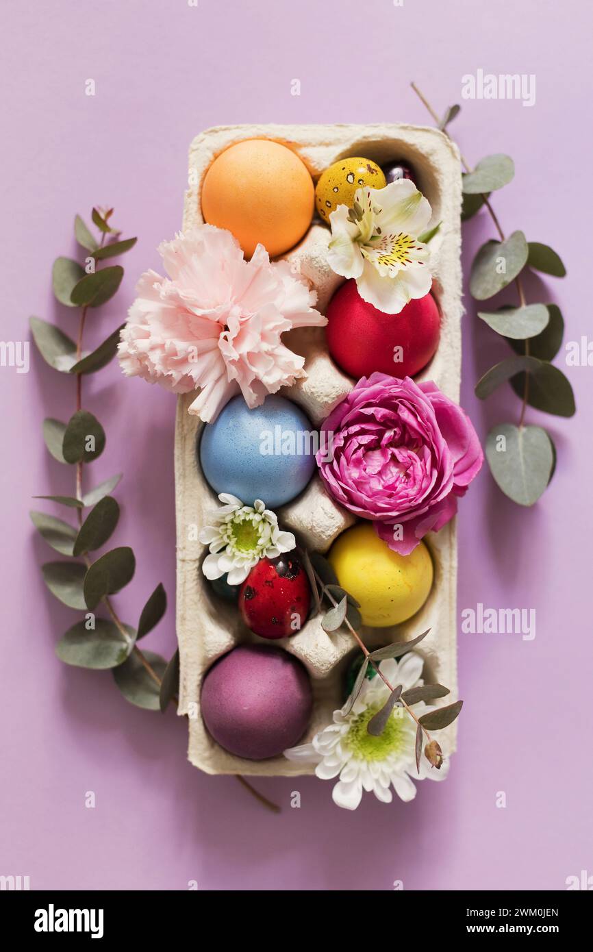 Farbenfrohe Ostereier mit Blumen auf rosa Hintergrund Stockfoto