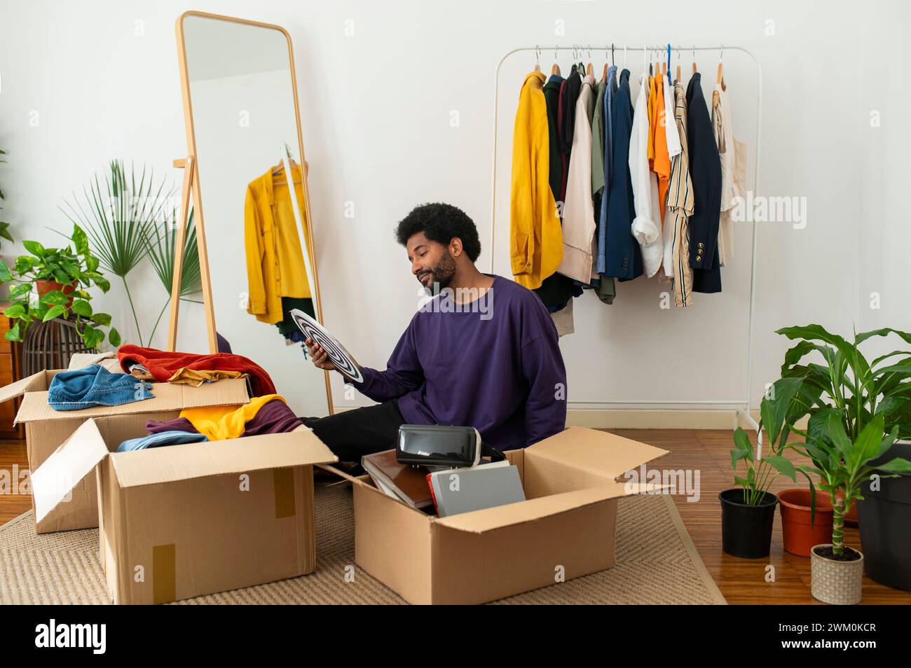 Junger Mann, der zu Hause Kleidung und Gegenstände entwirrt Stockfoto