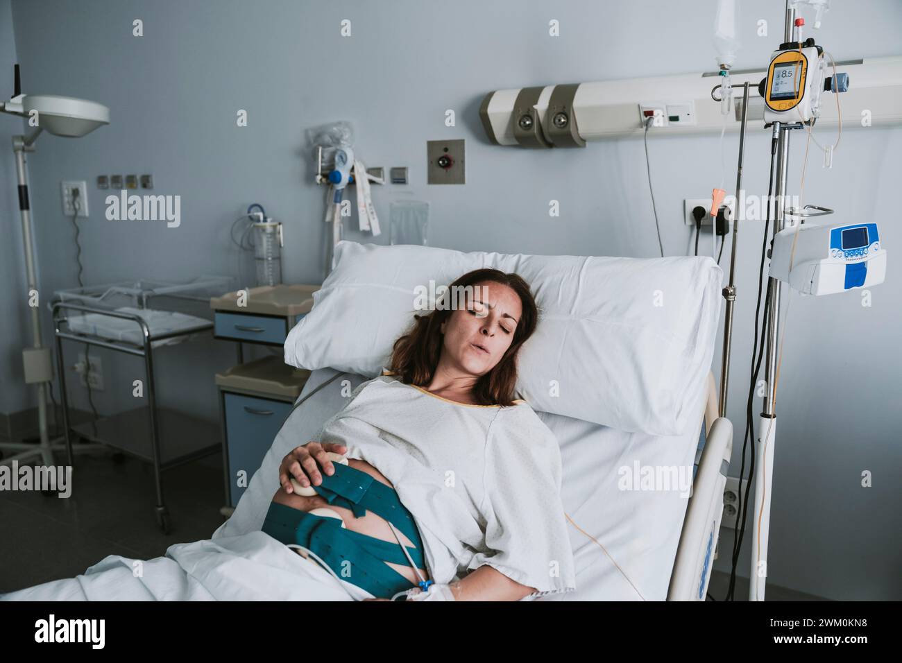 Schwangere Frau mit Schmerzen, die auf dem Krankenhausbett liegt Stockfoto