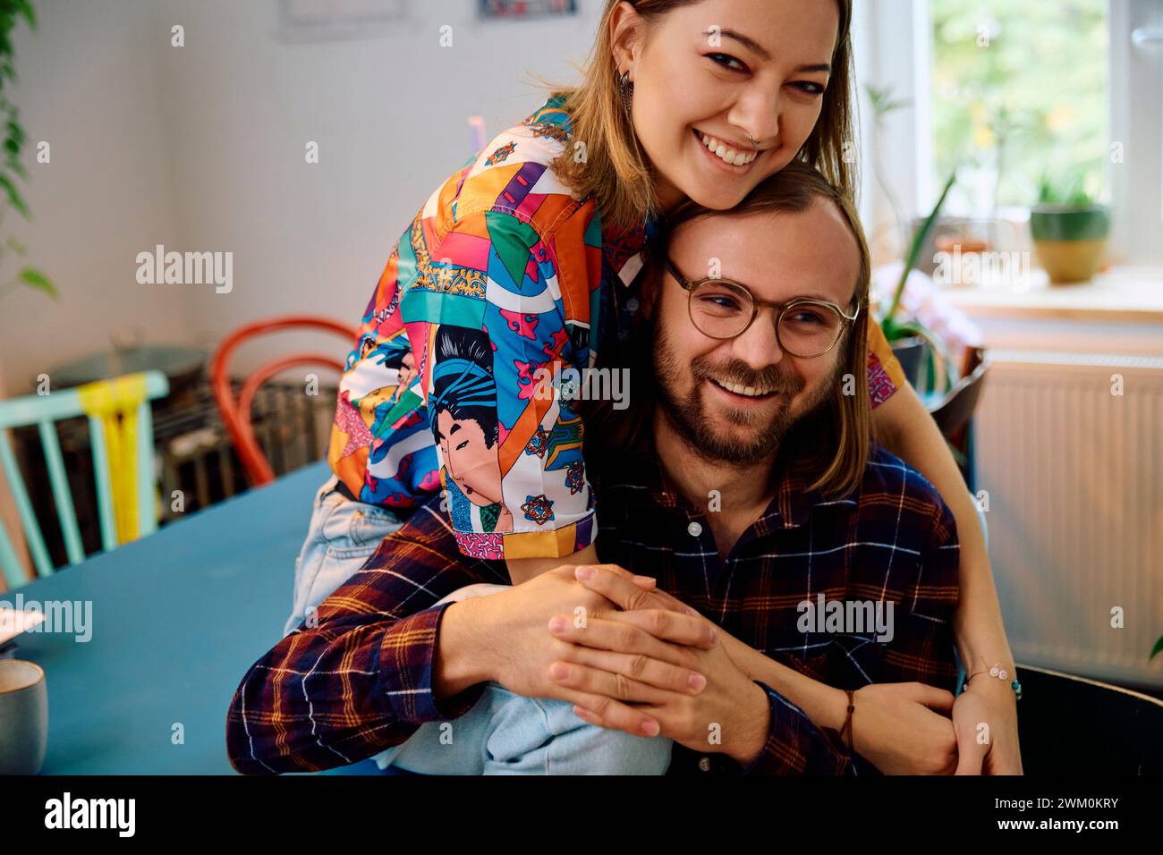 Glücklicher Mann mit Frau, die zu Hause auf dem Esstisch sitzt Stockfoto