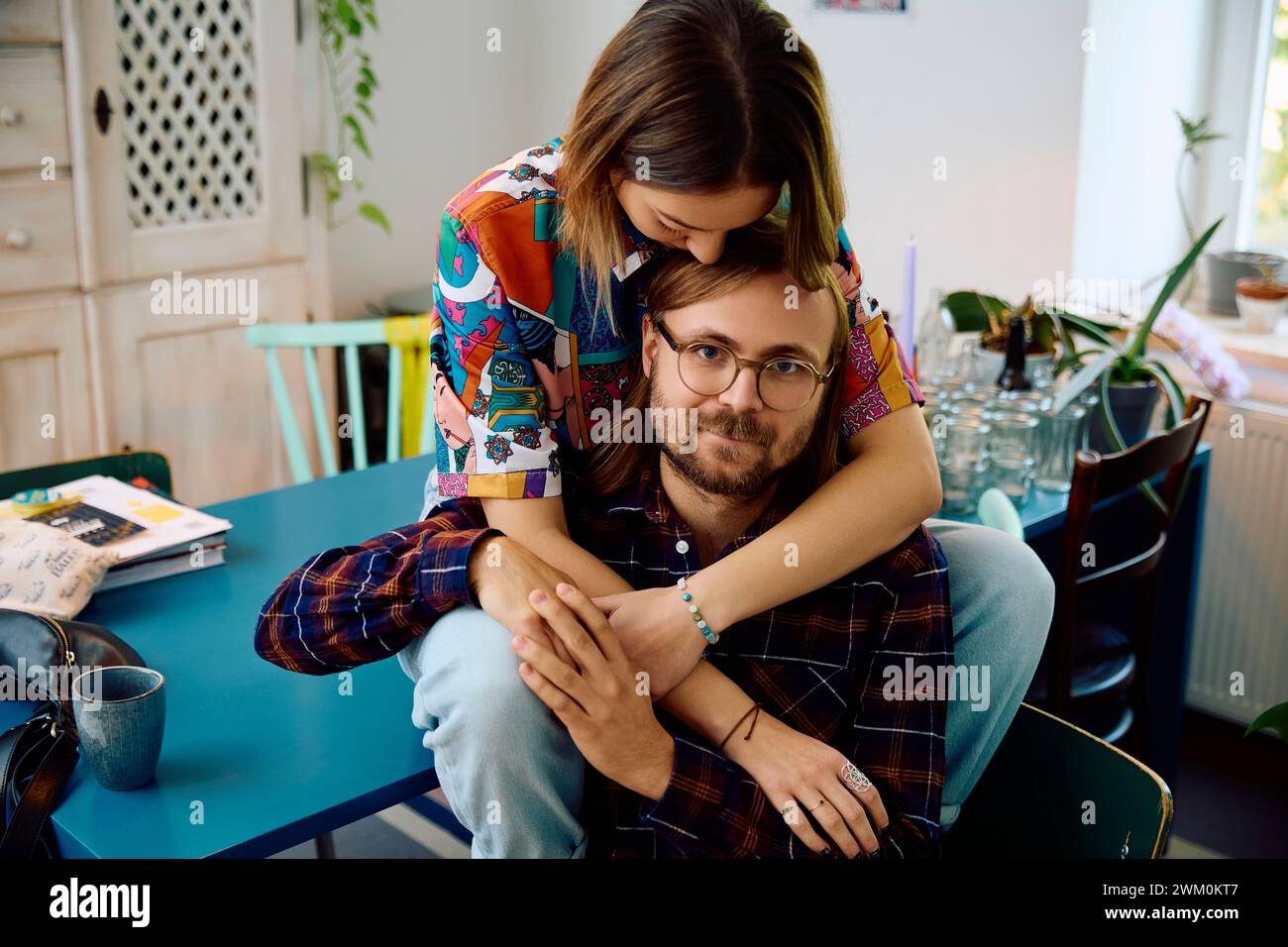 Lächelnder Mann mit Frau, die zu Hause auf dem Esstisch sitzt Stockfoto