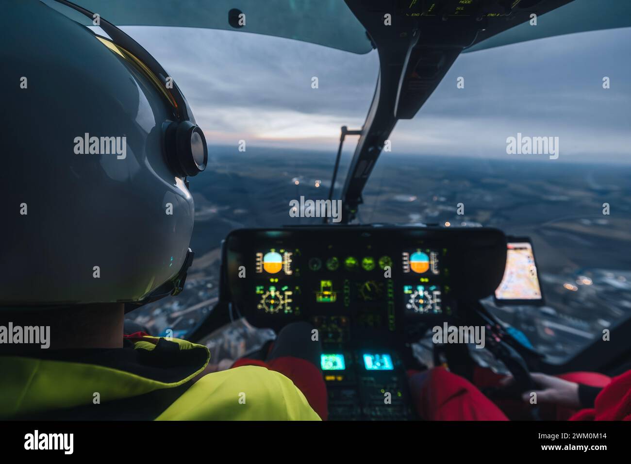 Pilot des Hubschraubernotfalldienstes, der in der Abenddämmerung über die Landschaft fliegt. Themen Notfallmedizin, Rettung und Notfallhilfe. Stockfoto