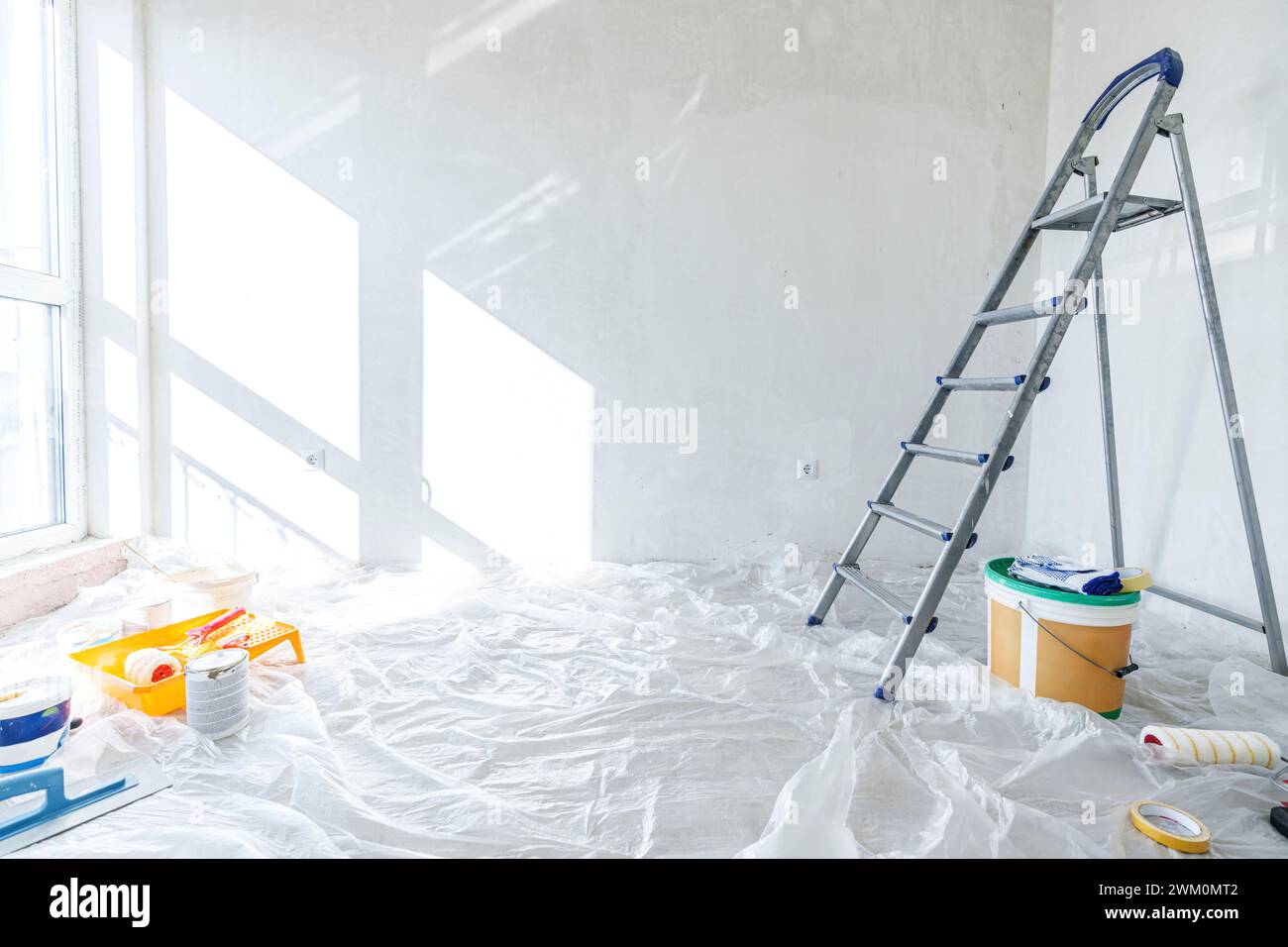 Lackiergeräte und Leiter auf dem mit Kunststoff bedeckten Boden zu Hause Stockfoto