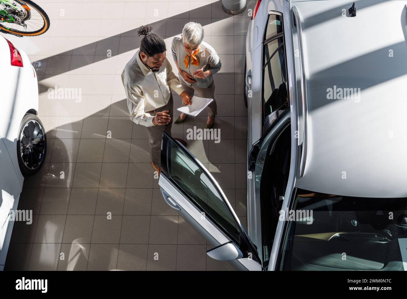 Verkaufsmitarbeiter bespricht das Fahrzeug mit dem Kunden im Ausstellungsraum Stockfoto