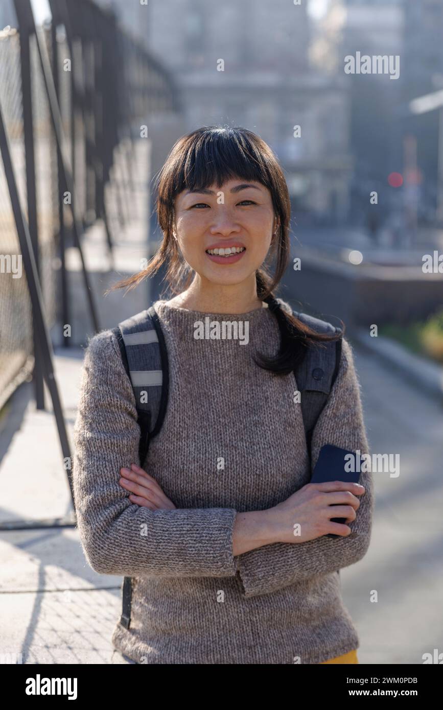Lächelnde reife Frau, stehend mit gekreuzten Armen Stockfoto