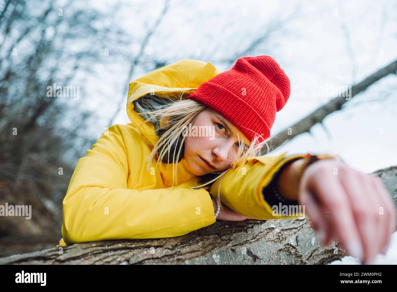 Ernsthafte junge Frau, die sich auf Baumstamm stützt Stockfoto