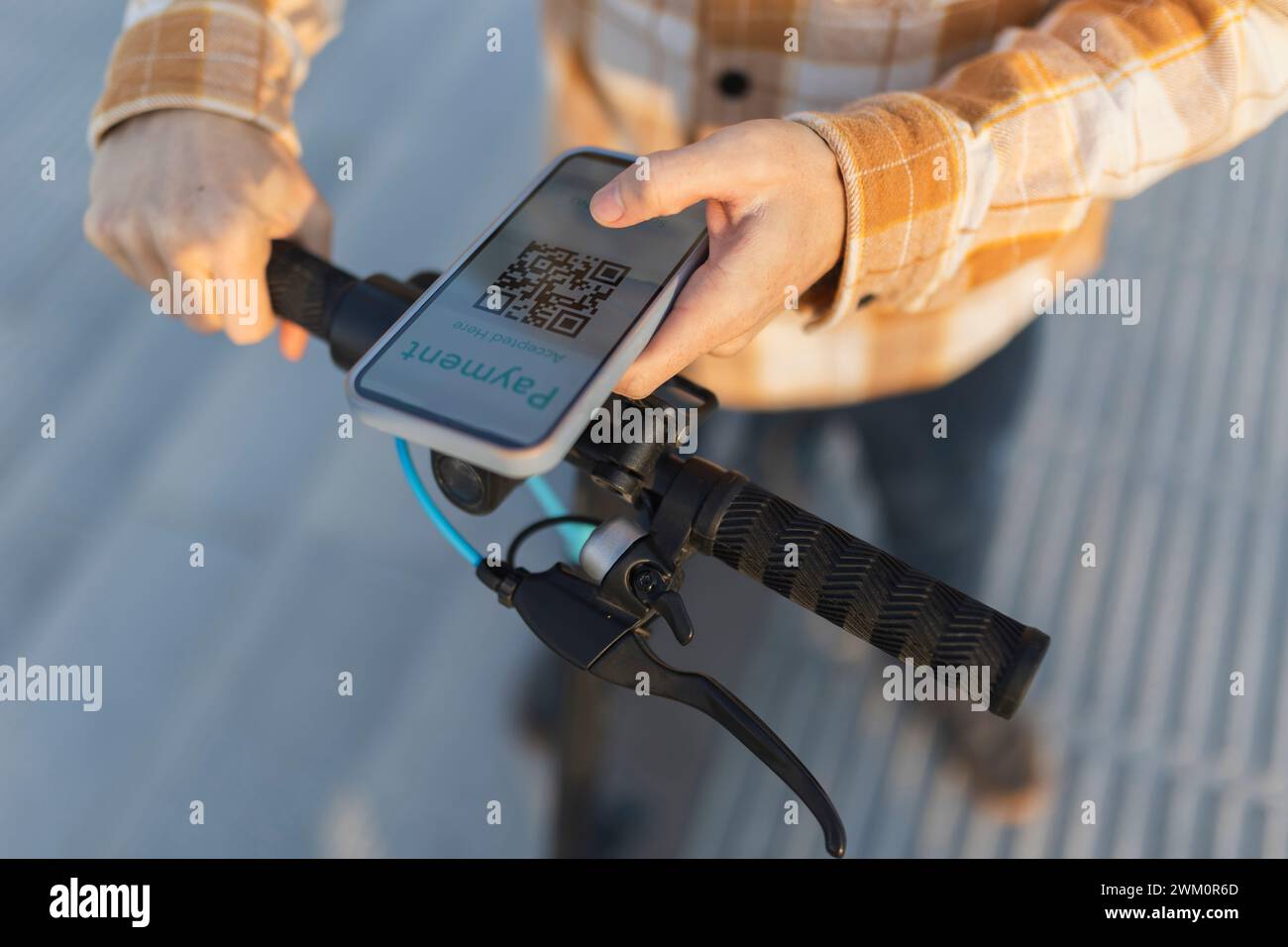 Mann scannt QR-Code und mietet einen elektrischen Roller Stockfoto