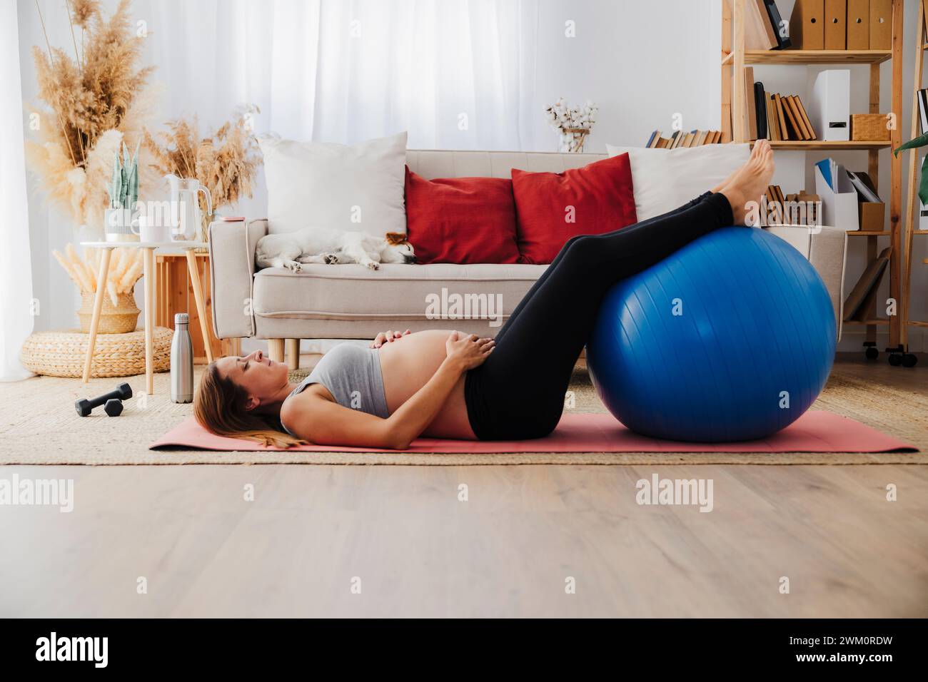 Schwangere Frau liegend auf Yogamatte mit Fitnessball zu Hause Stockfoto