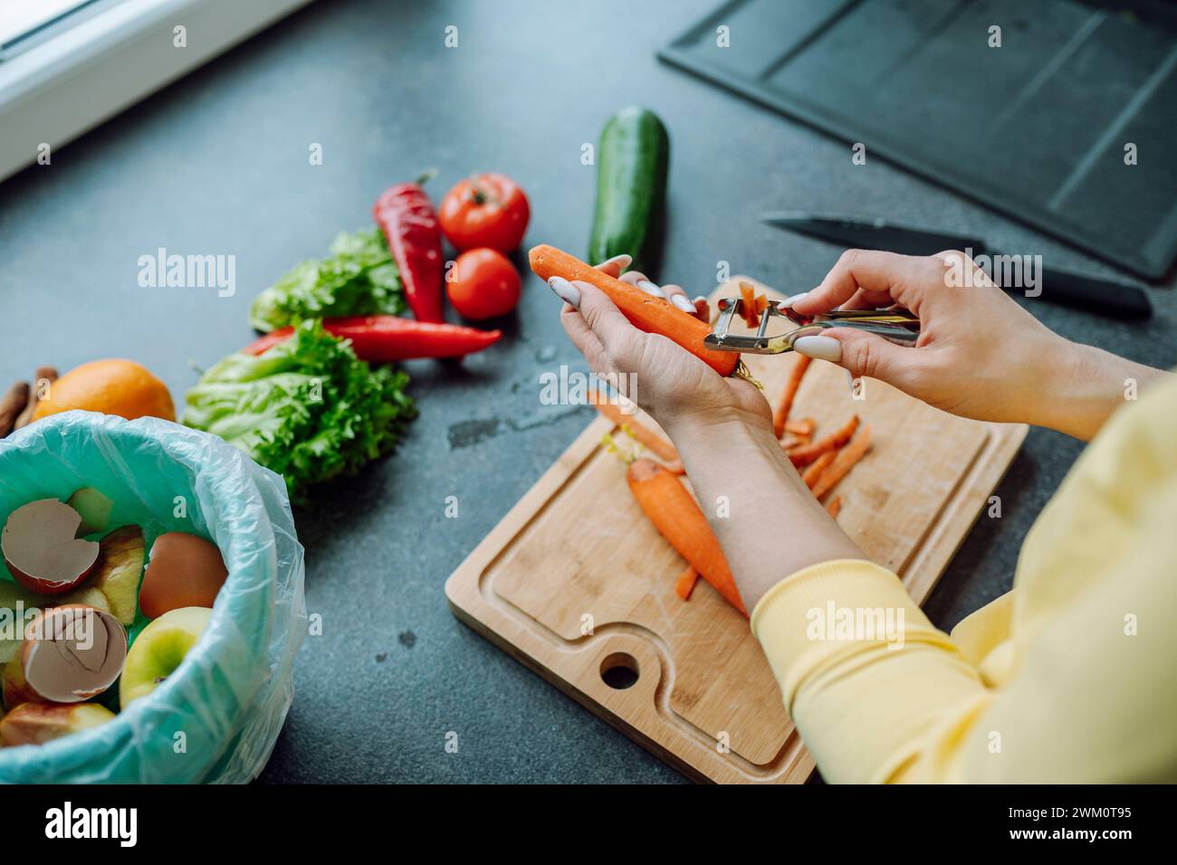 Hände einer jungen Frau, die Karotten in der Küche zu Hause schält Stockfoto