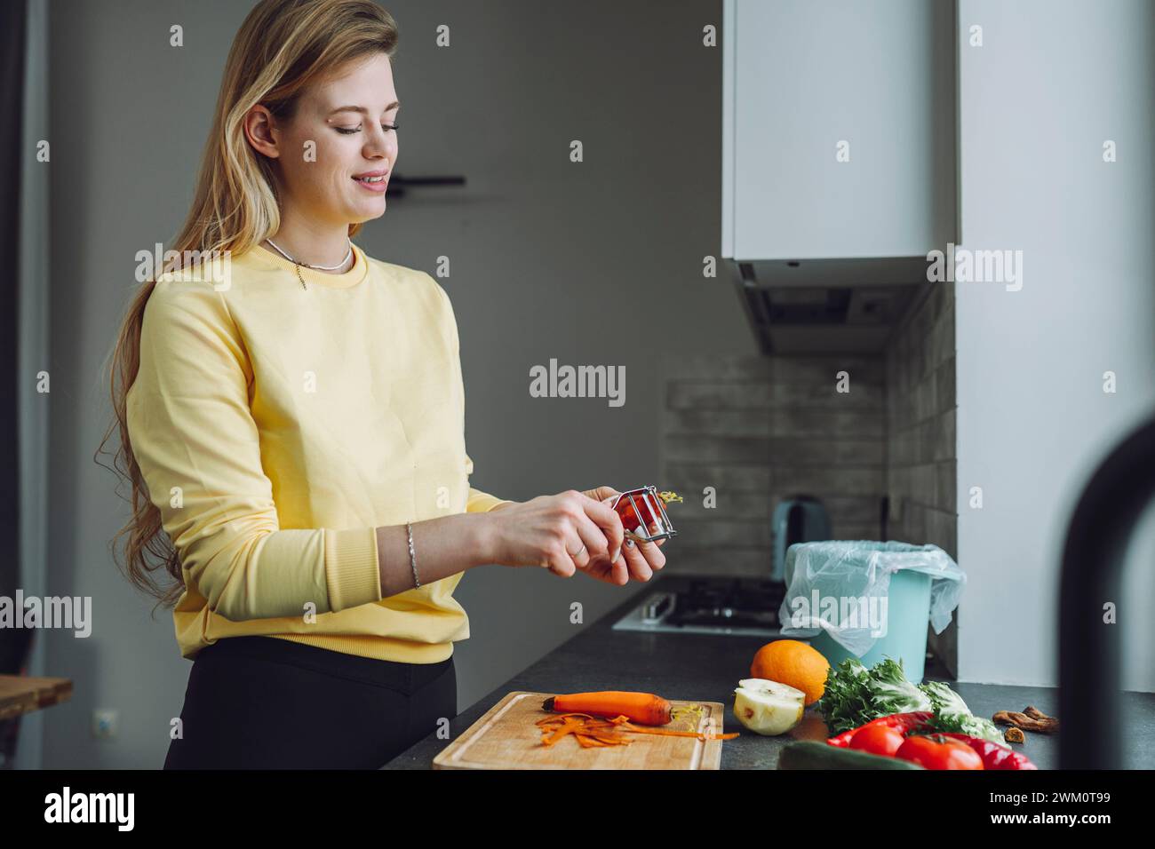 Junge Frau schält Gemüse in der Küche zu Hause Stockfoto