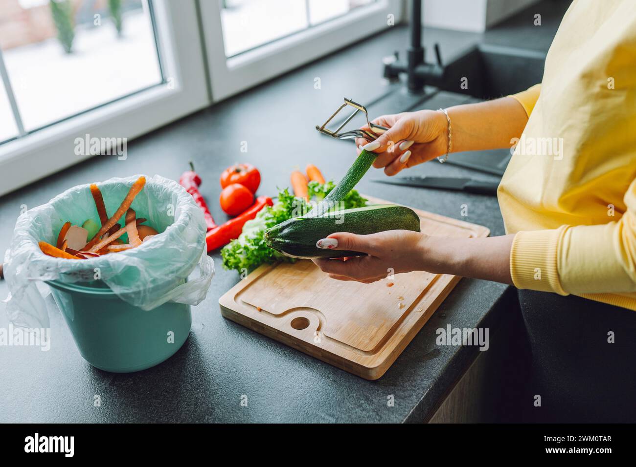 Hände einer jungen Frau, die Zucchini auf der Küchenzeile zu Hause schält Stockfoto