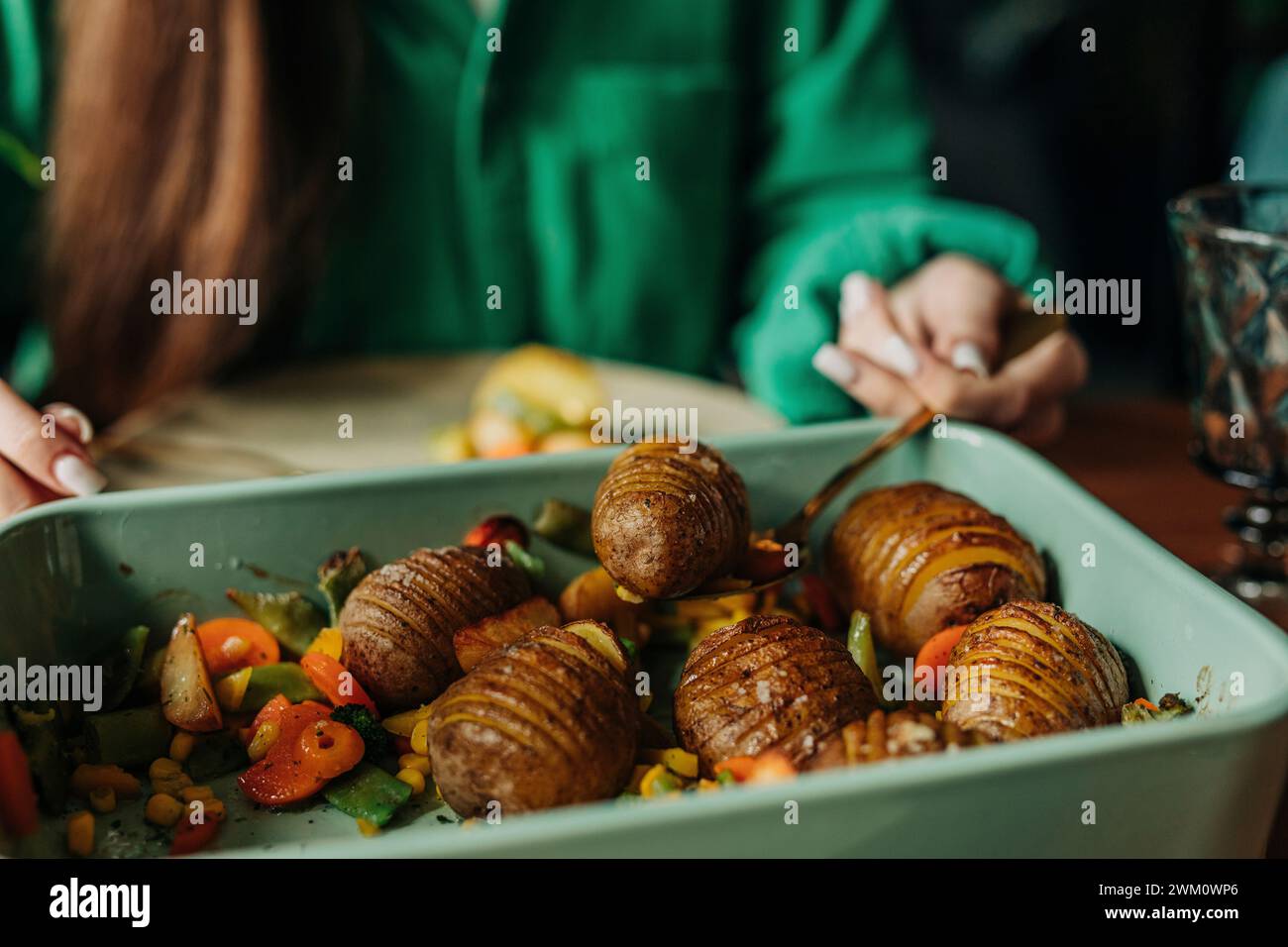 Frau, die beim Osteressen frisch gebackene Kartoffeln aus Auflaufform holt Stockfoto