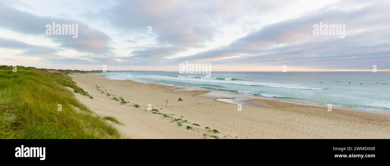 Panoramaaufnahme eines Strandes in Norwegen mit wunderschönen Wolken Wellen, die sanft das Ufer eines malerischen Strandes in Norwegen streicheln, während der Himmel von brennt Stockfoto