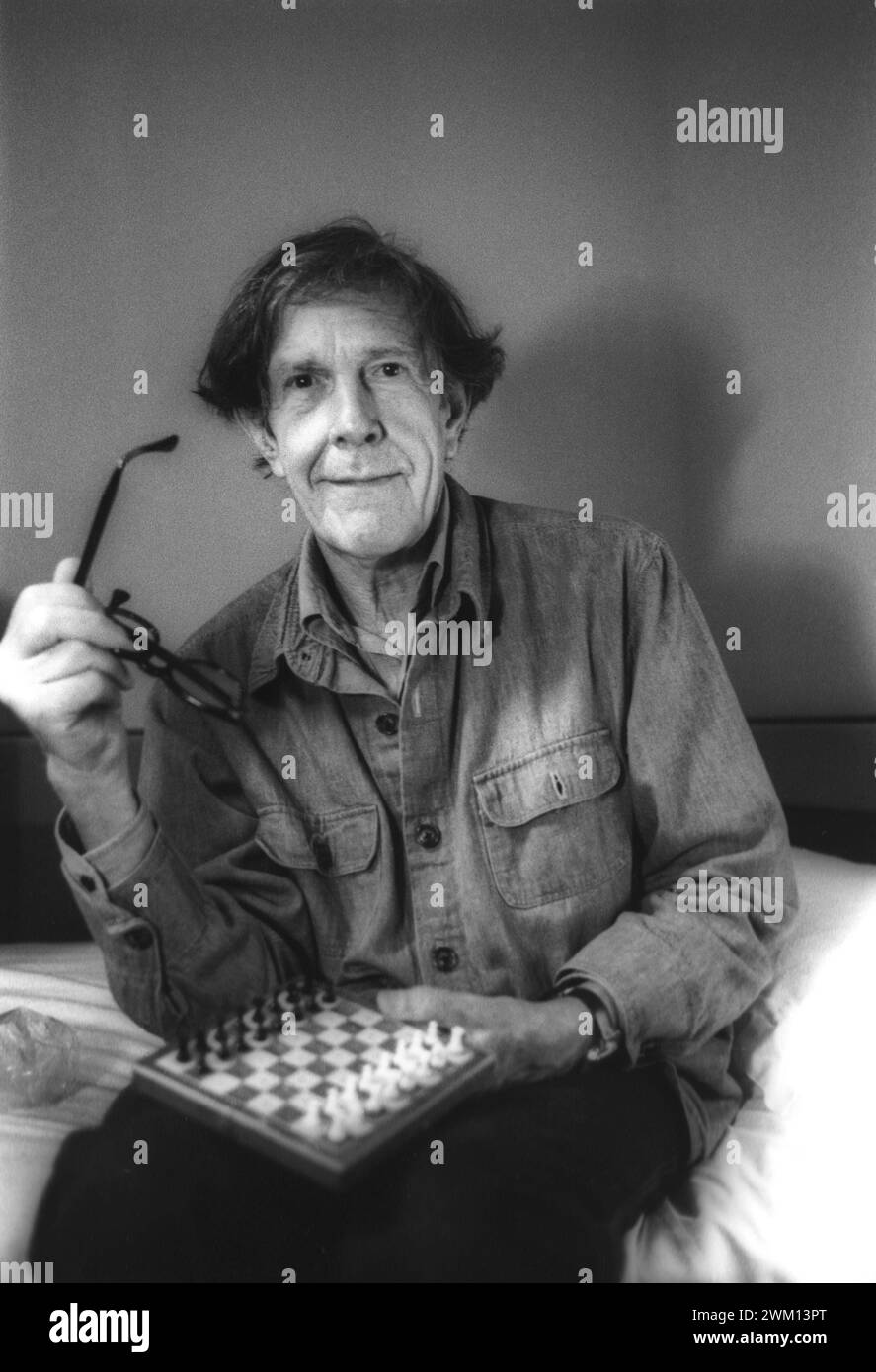 3827904 John Cage; (add.info.: Venedig, 1982. Der amerikanische Komponist John Cage sitzt auf dem Bett mit einem Schachbrett in seinem Hotelzimmer / Venedig, 1982. IL compositore John Cage seduto sul letto con una scacchiera nella sua stanza d'albergo); © Marcello Mencarini. Alle Rechte vorbehalten 2024. Stockfoto