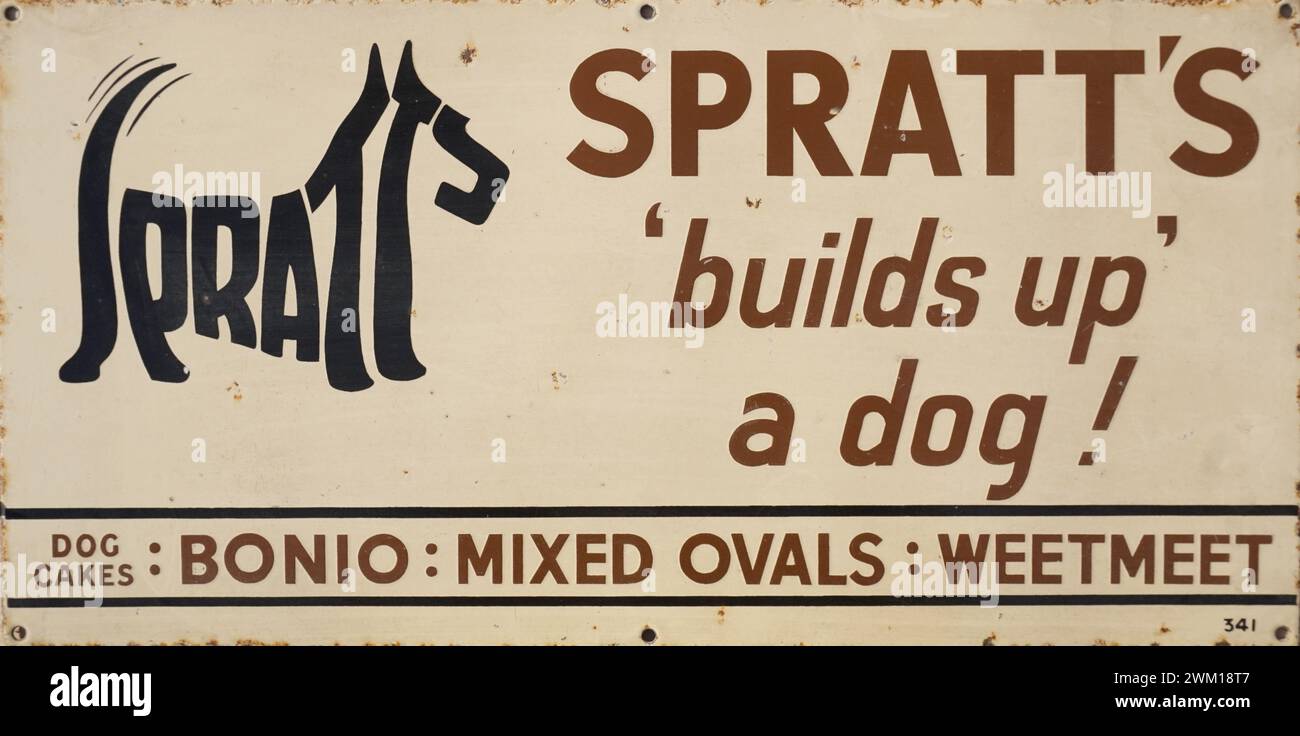 Emaillewerbung aus den 1930er Jahren Spratt's Hundefutter. Spratts baut einen Hund auf. Schöne Illustration eines Terrierhundes, hergestellt aus den Buchstaben des Namens Spratts, ikonisches Design-Logo, bekannt als Kalligramm. Hersteller von Bonio, Mixed Ovals und Weetmeet. Emailschilder wurden von den Herstellern geliefert, um an Ladenfronten zu befestigen, um Waren zu werben. Sie sind aus Metall gefertigt und sind robust und langlebig, als Produkte viel länger als heute in der Herstellung waren. Heute sind diese emaillierten Schilder in hohem Maße sammelbar und sogar gefälscht. Stockfoto