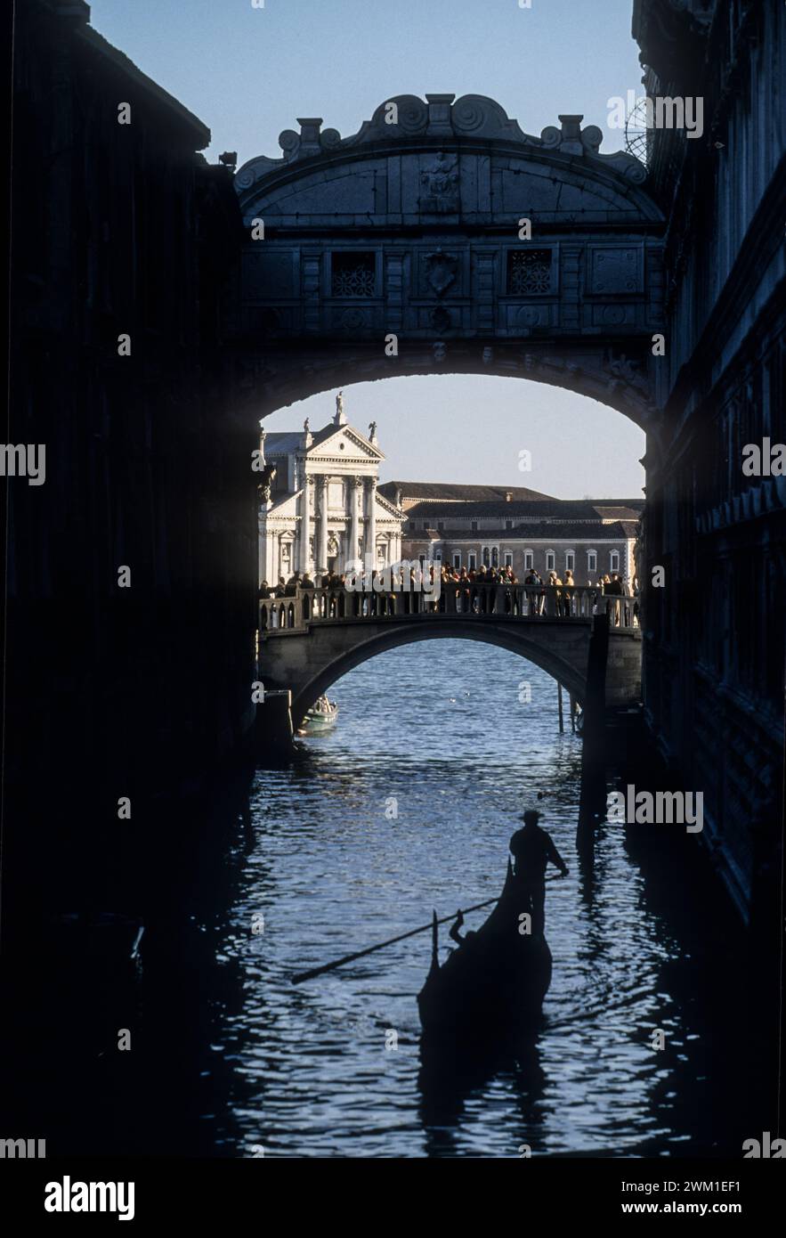 4067962 Venedig, 1998. Brücke der Sehenswürdigkeiten im Vordergrund. Diese 1602 erbaute Brücke führt über den Rio di Palazzo und verbindet die neuen Gefängnisse mit den alten Gefängnissen im Dogenpalast. Sein Name ist, weil die Sträflinge es vor ihrer Inhaftierung durchgesehen haben. Eine örtliche Legende besagt, dass Liebenden ewige Liebe gewährt wird, wenn sie sich bei Sonnenuntergang unter der Brücke in einer Gondel küssen; (add.info.: Venedig, 1998. Brücke der Sehenswürdigkeiten im Vordergrund. Diese 1602 erbaute Brücke führt über den Rio di Palazzo und verbindet die neuen Gefängnisse mit den alten Gefängnissen im Dogenpalast. Sein Name ist wegen der Co Stockfoto