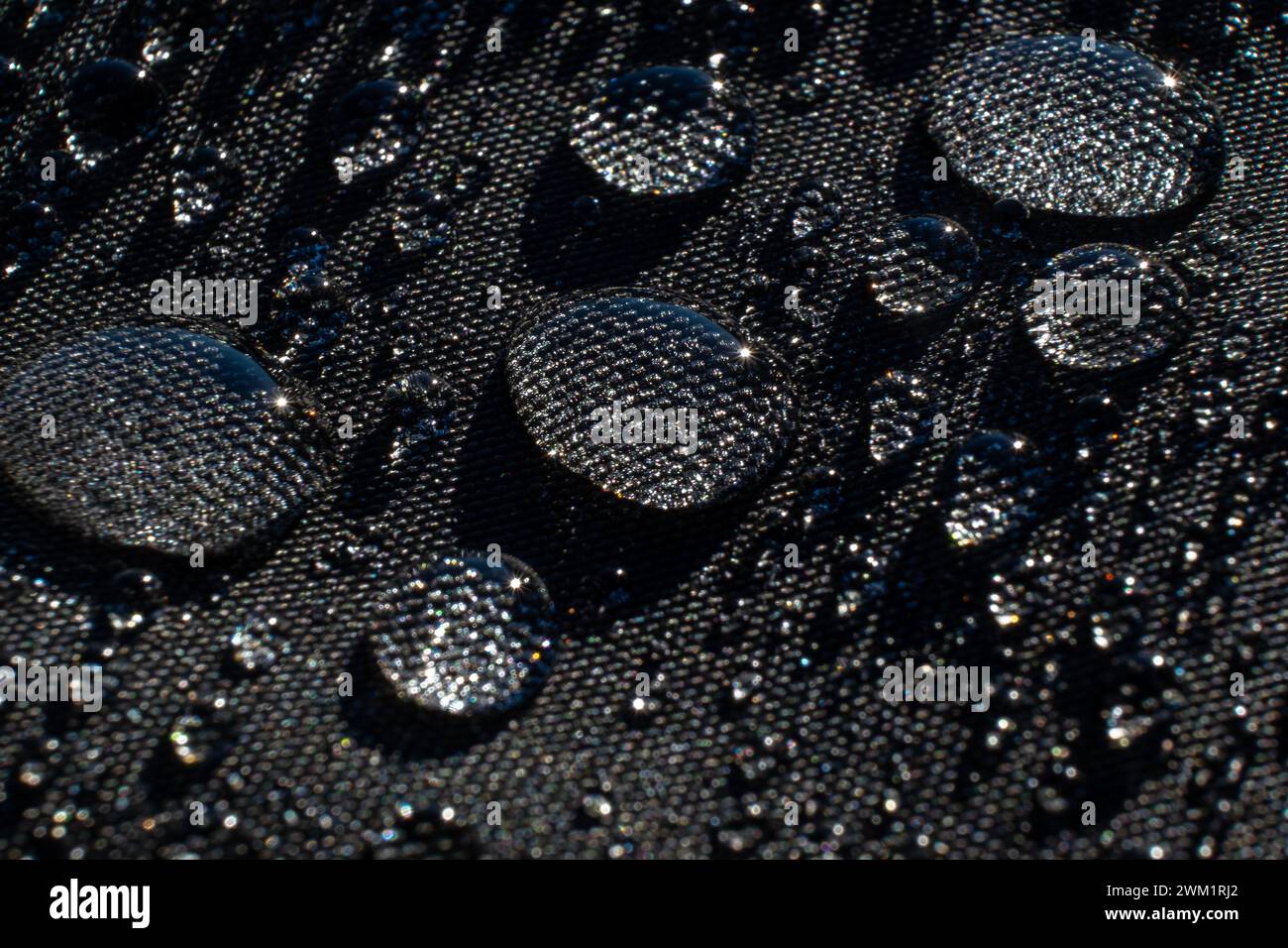 Wassertropfen auf wasserdichtem schwarzem Stoff Stockfoto