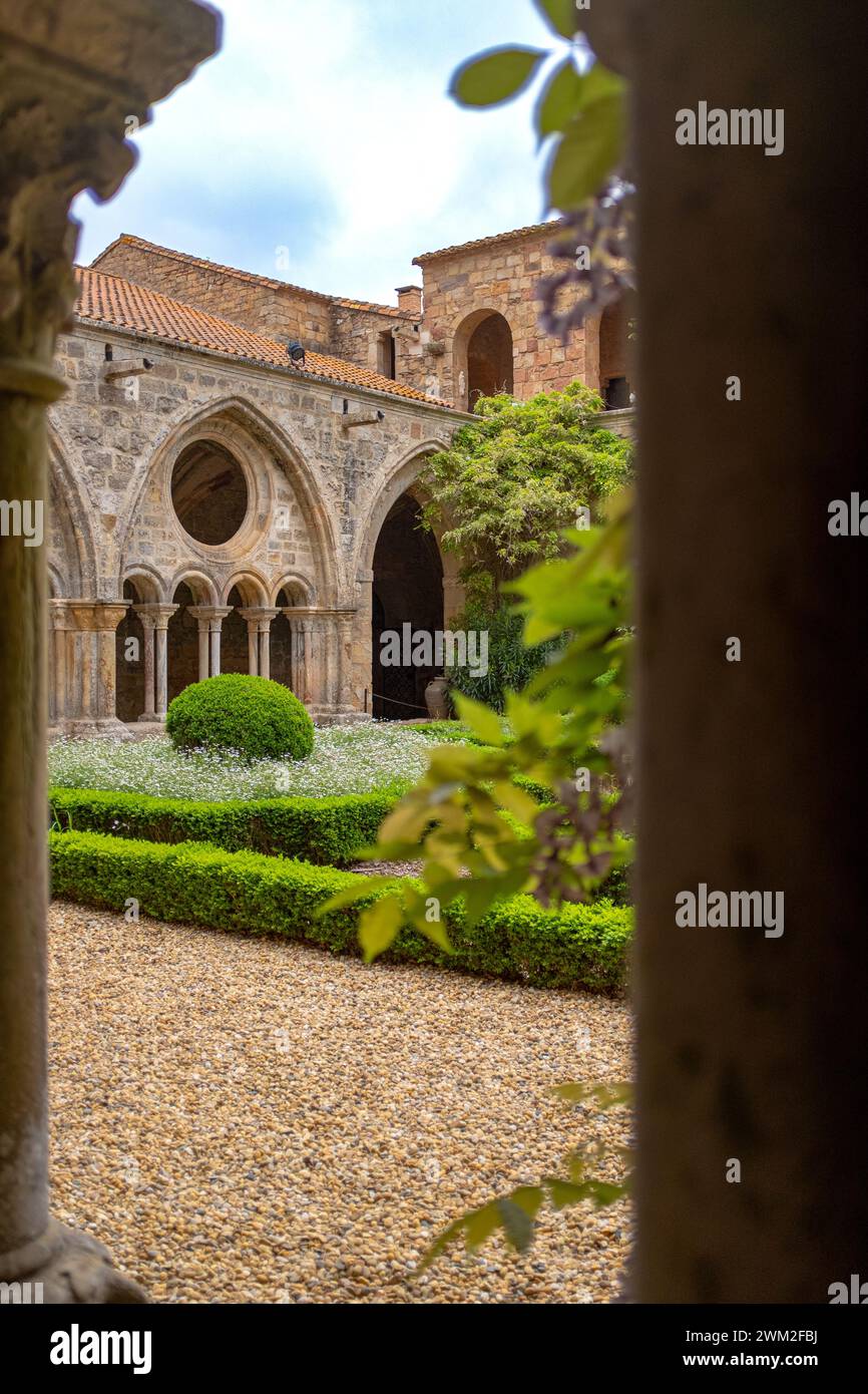 Vertikale Aufnahme des Kreuzgangs der Abtei Fontfroide in Frankreich. Foto an einem sonnigen Frühlingstag durch eine Kolonnade ohne Menschen Stockfoto