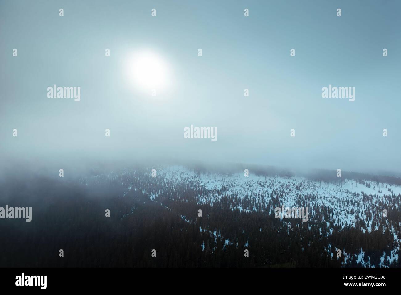 Aus der Vogelperspektive auf die schneebedeckte Bergkette mit Sonnenschein an frostigen Tagen. Moody Winterlandschaft. Stockfoto