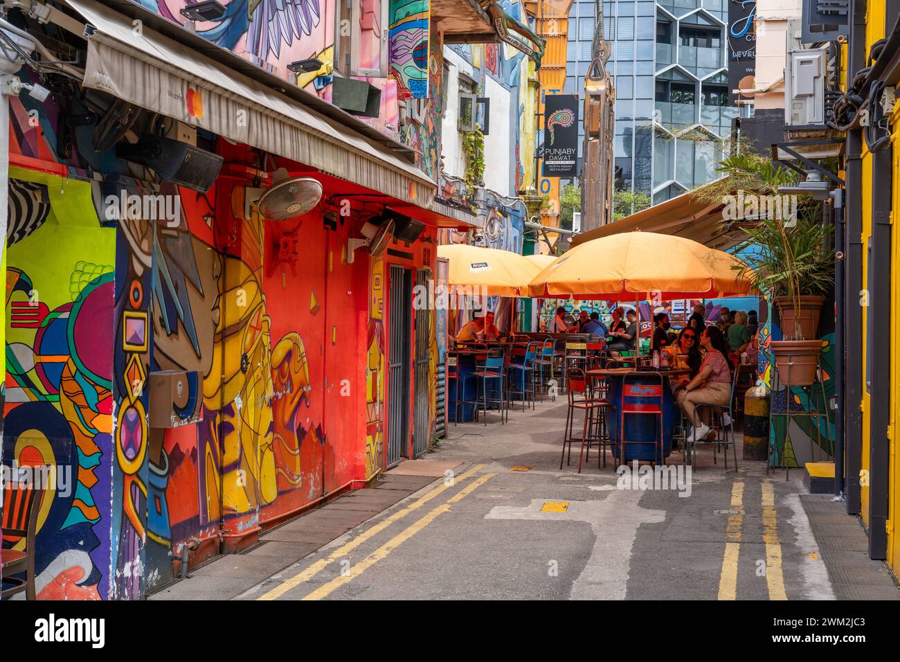 Tische und Sonnenschirme säumen eine gemütliche Straßenecke Stockfoto