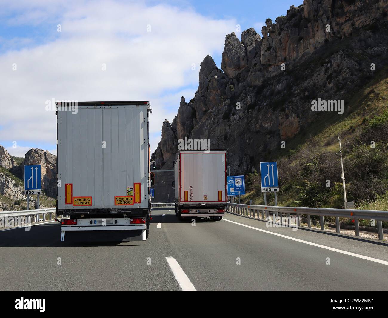 Hinter überholenden Lastkraftwagen auf steiler zweispuriger Autobahn durch Berge, die andere Verkehrsteilnehmer blockieren Stockfoto