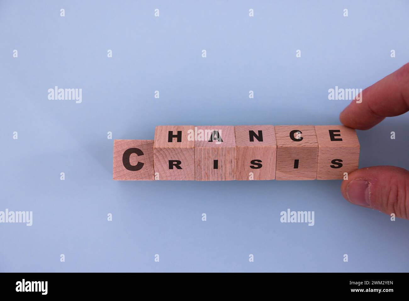 Holzwürfel mit der Hand umdrehen, um den Wortlaut „Krise zu „Chance“ zu ändern. Die Einstellung ist wichtig für die menschliche Entwicklung. Stockfoto