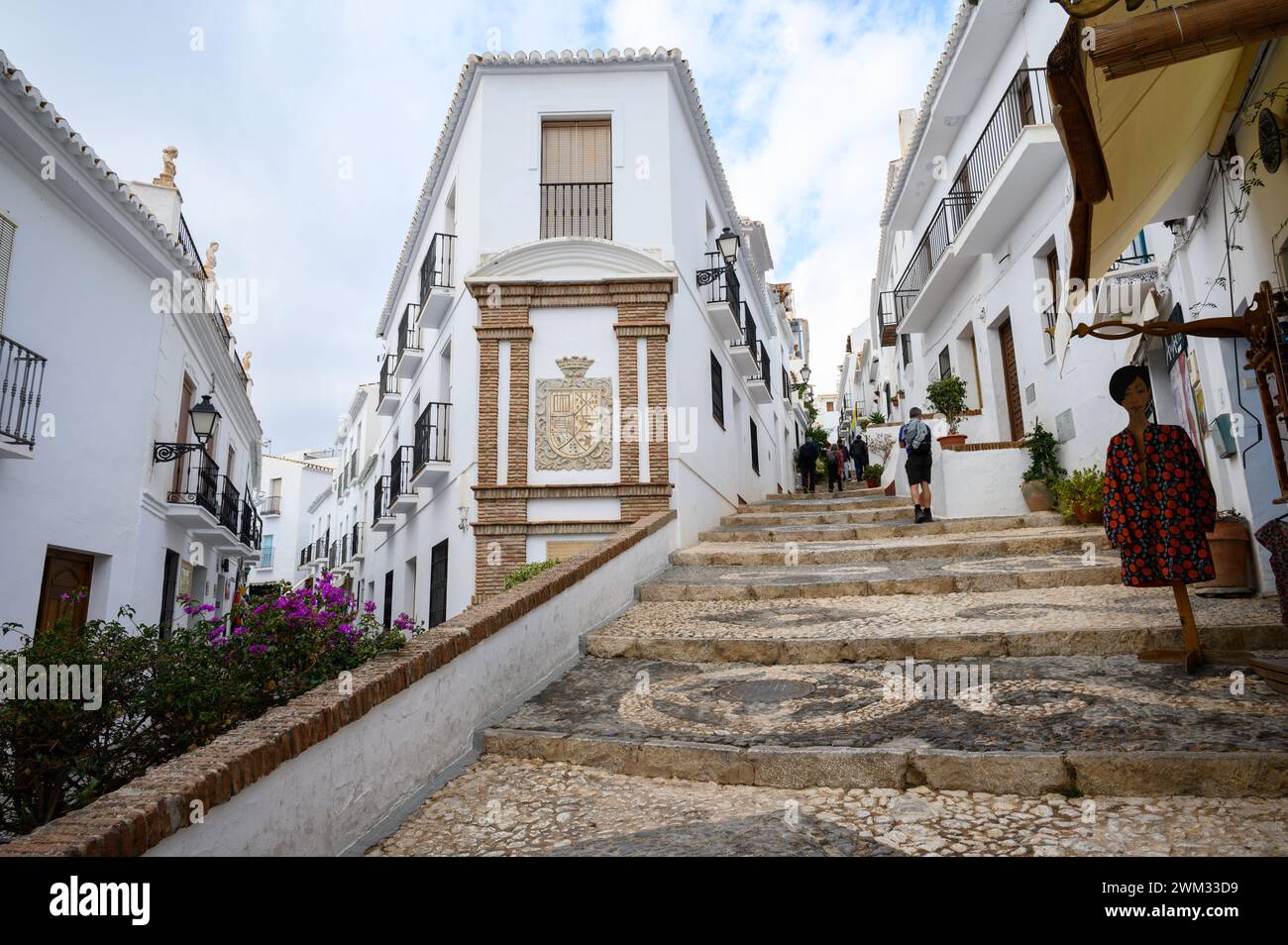 Bergab und steile Straßen bergauf, wo Menschen in einem der schönsten Dörfer Spaniens, Frigiliana, Malaga, Spanien, spazieren gehen. Stockfoto