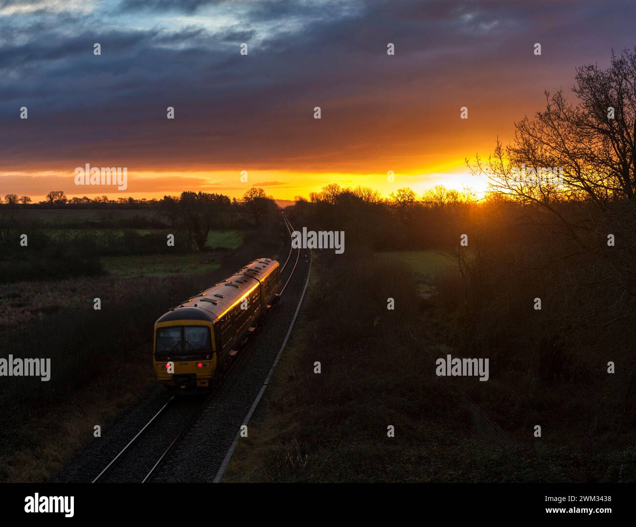 Erster Great Western Turbo Train 165120 in Burleigh auf der eingleisigen Cotswolds-Bahnstrecke bei aufgehender Sonne Stockfoto