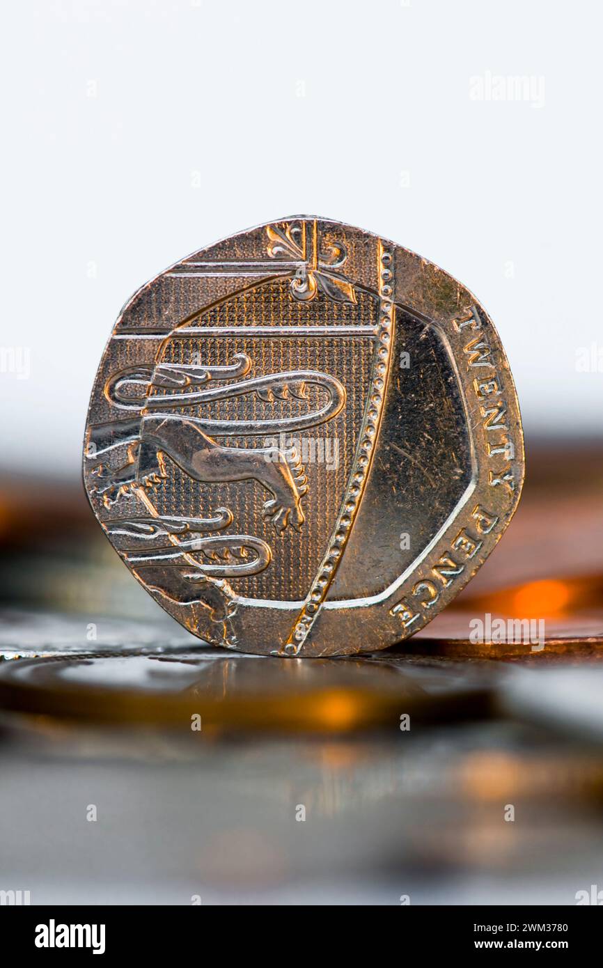Studio-Aufnahme von einem 20 Pence in Sterling-Währung, das aufrecht auf dem Tisch steht, mit unscharfen Münzen im Vordergrund Stockfoto
