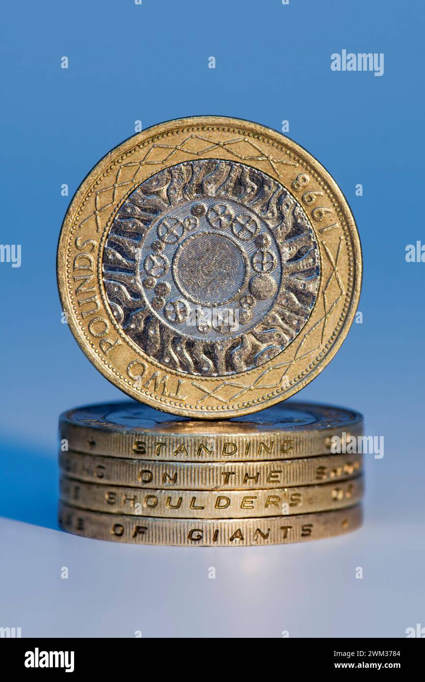 Studio-Aufnahme von zwei-Pfund-Sterling-Münzen im Stapel, die „auf den Schultern von Riesen stehen“ mit einer aufrechten zwei-Pfund-Münze, die oben ausgeglichen ist, aga Stockfoto