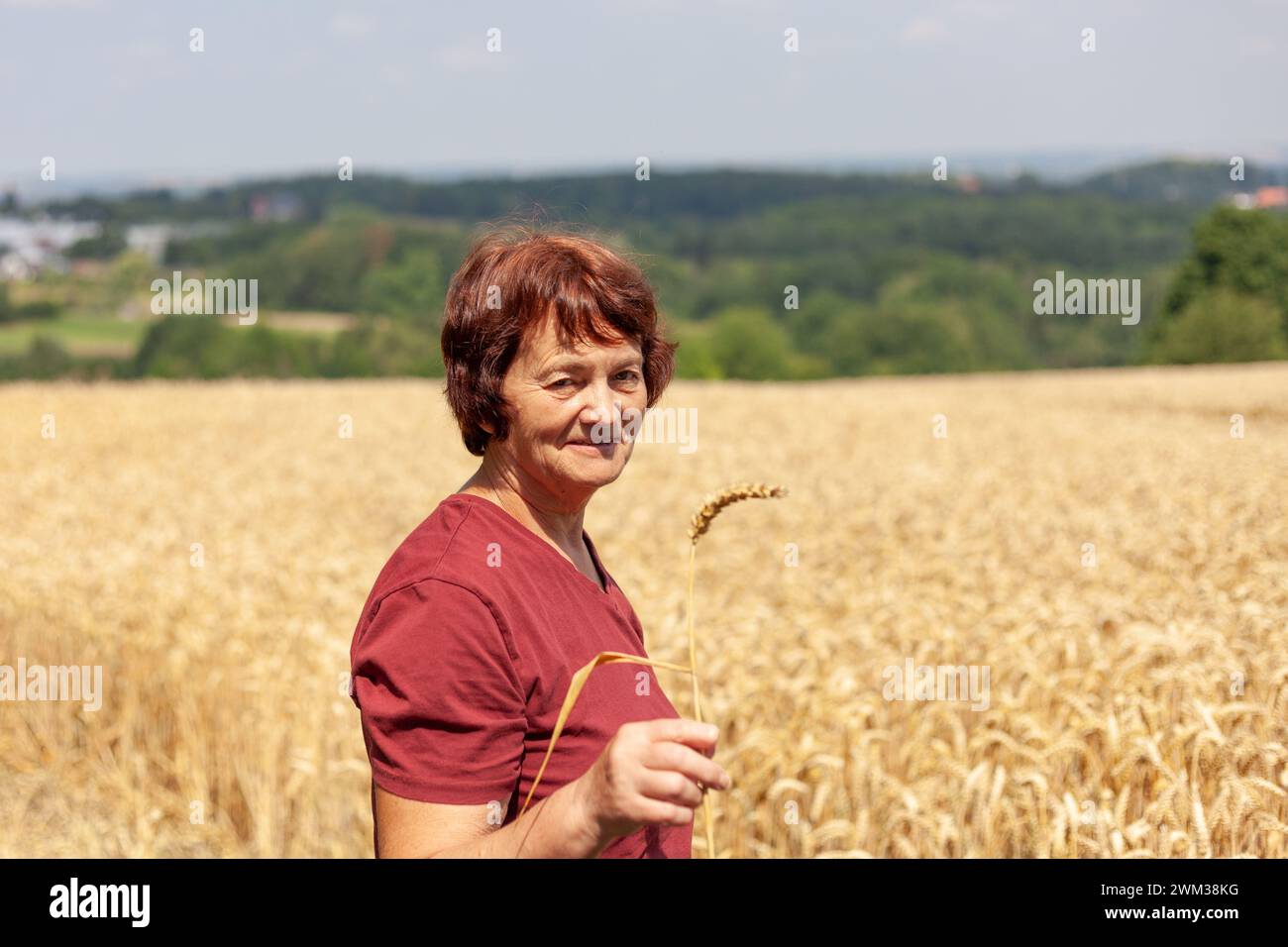 Porträt einer lächelnden Seniorin, die auf einem Weizenfeld steht. Stockfoto