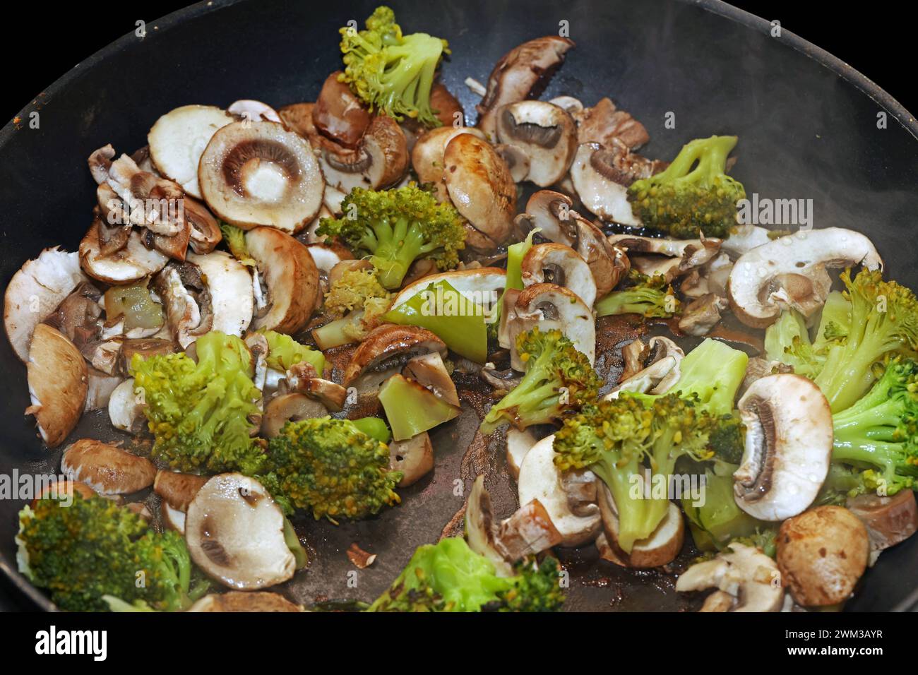 Vegane Gemüseküche Brokkoli und Champignons während der Zubereitung in einer Bratpfanne *** Vegan Gemüseküche Brokkoli und Pilze während der Zubereitung in einer Pfanne Stockfoto