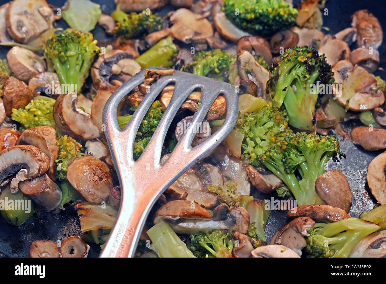 Vegane Gemüseküche Brokkoli und Champignons während der Zubereitung in einer Bratpfanne *** Vegan Gemüseküche Brokkoli und Pilze während der Zubereitung in einer Pfanne Stockfoto