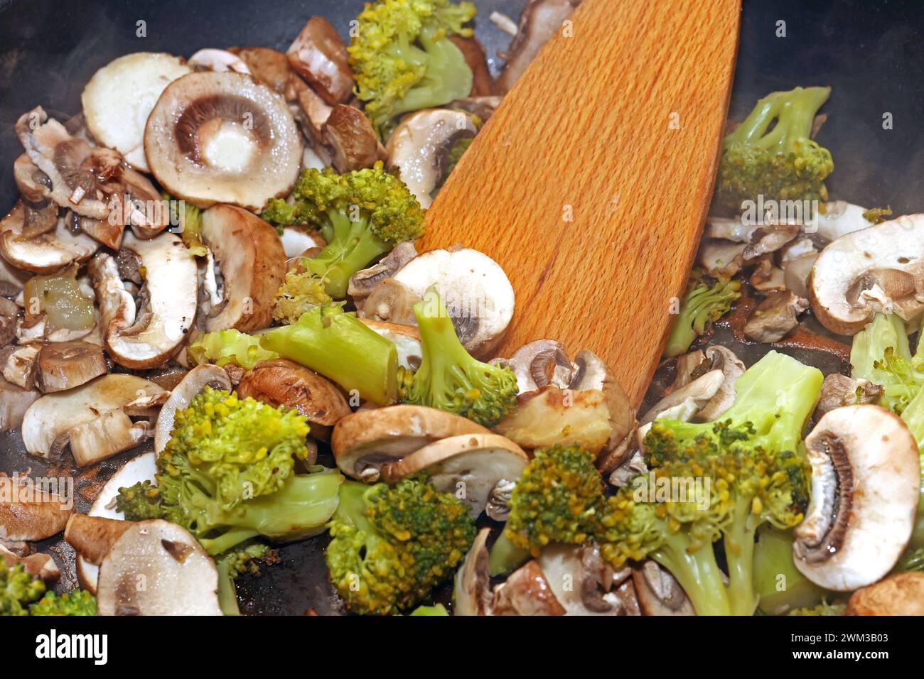 Vegane Gemüseküche Brokkoli und Champignons während der Zubereitung in einer Bratpfanne *** Vegan Gemüseküche Brokkoli und Pilze während der Zubereitung in einer Pfanne Stockfoto