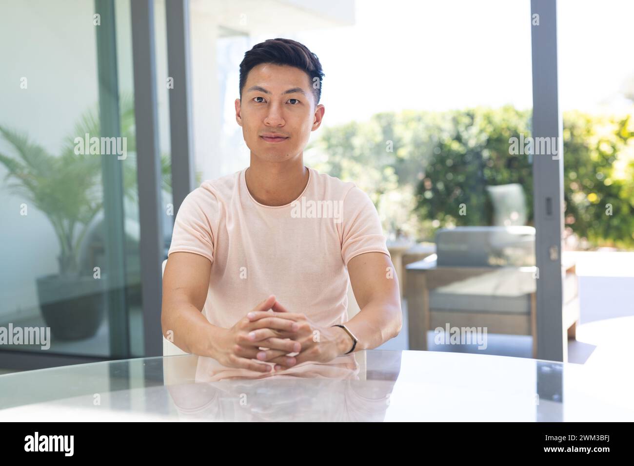 Ein junger asiatischer Mann saß in einem modernen Home-Office auf einem Videoanruf Stockfoto