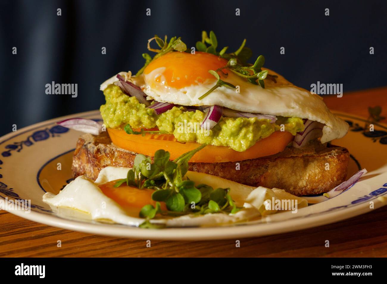 Sehr lecker aussehender Toast mit Rührei mit Tomaten, Salat und Avocadodressing Stockfoto