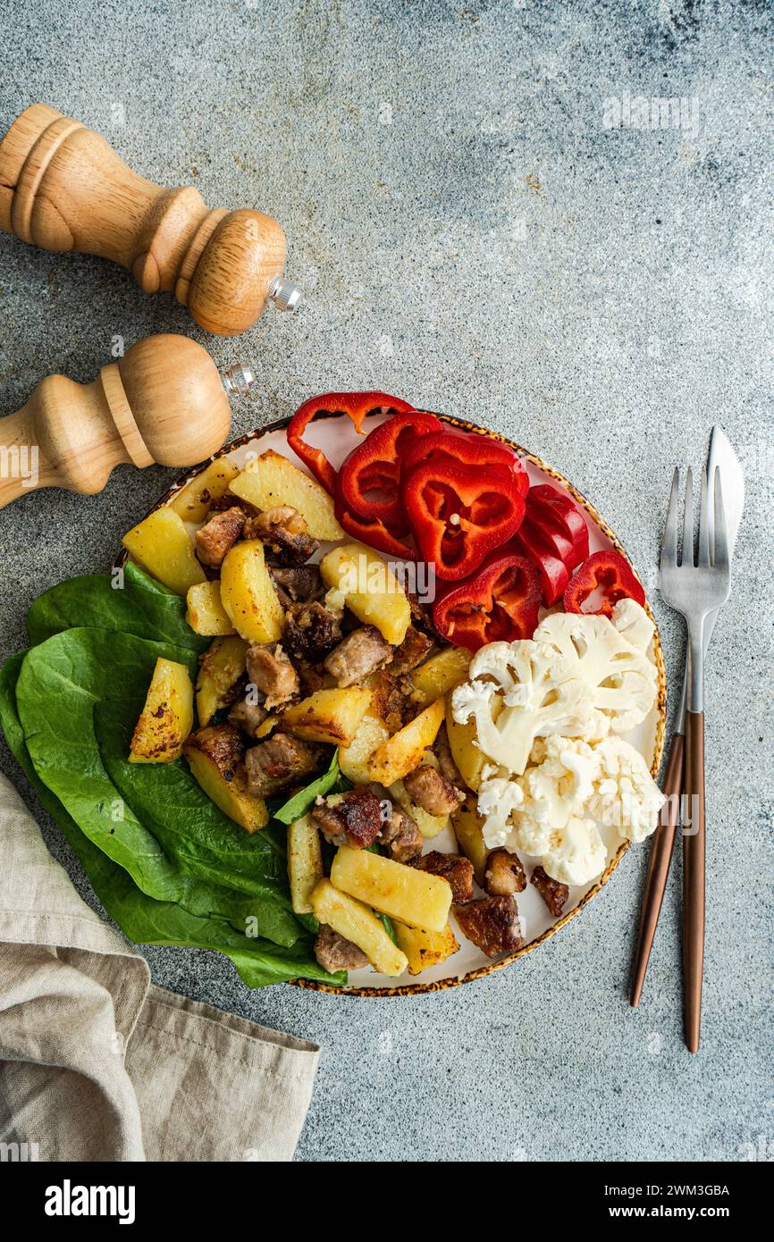 Gesundes Mittagessen mit frischem Paprika, Blumenkohl, Spinat und gebratenen Kartoffeln und Fleisch Stockfoto