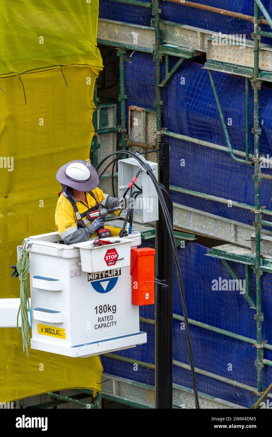 Elektrizitätsleitung arbeitet an der Stromleitungsinfrastruktur von einer Hubschaufel aus. Stockfoto