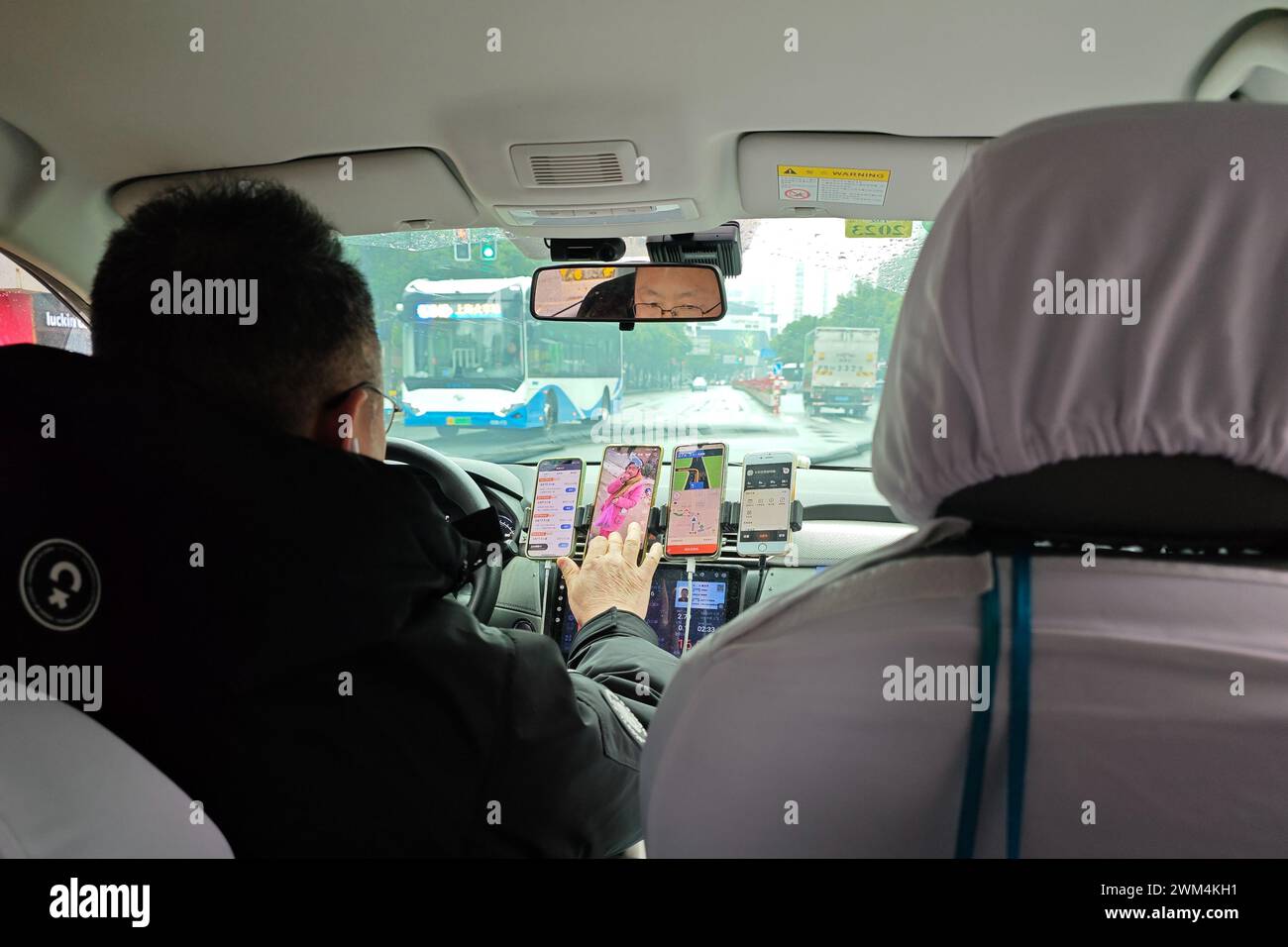 SHANGHAI, CHINA - 24. FEBRUAR 2024 - ein online fahrender Fahrer hat fünf Mobiltelefone auf beiden Seiten des Fahrersitzes, um es einfacher zu nehmen Stockfoto