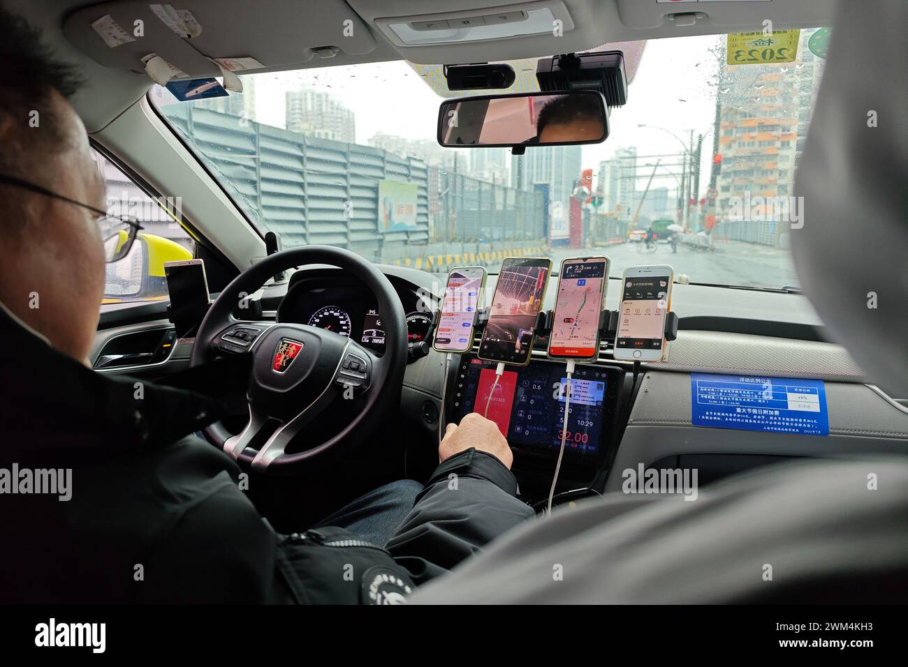 SHANGHAI, CHINA - 24. FEBRUAR 2024 - ein online fahrender Fahrer hat fünf Mobiltelefone auf beiden Seiten des Fahrersitzes, um es einfacher zu nehmen Stockfoto