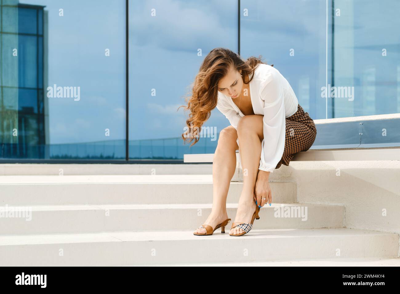 Geschäftsfrau, die in Eile den Riemen an ihren Sandalen festlegt Stockfoto